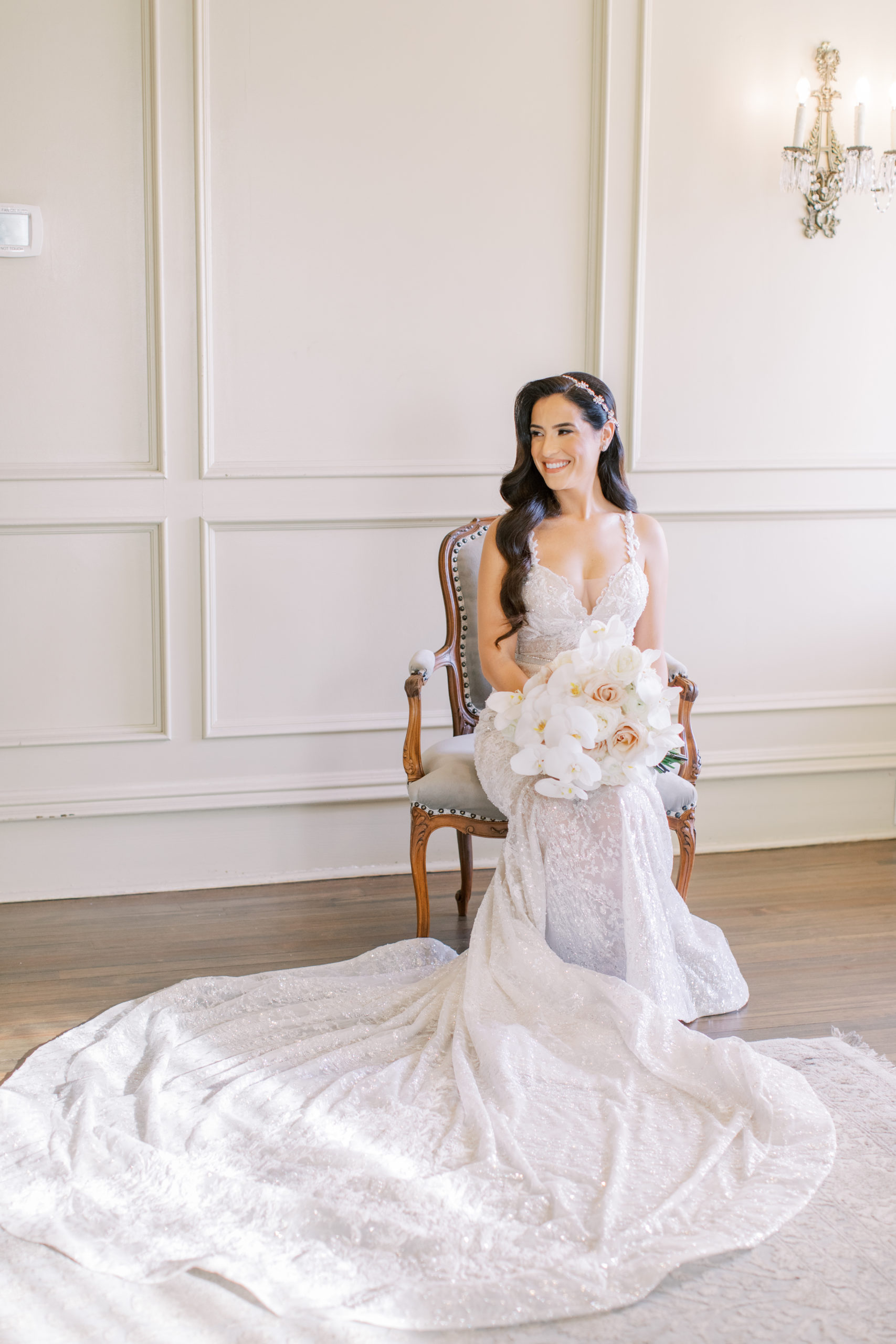 bride seated holding bouquet of roses and orchids - Park Savoy Wedding Photography