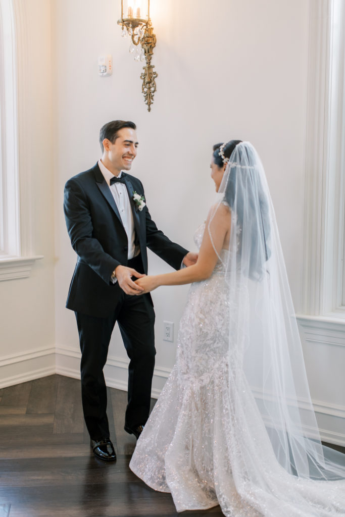 groom smiles at bride during first look in wedding chapel