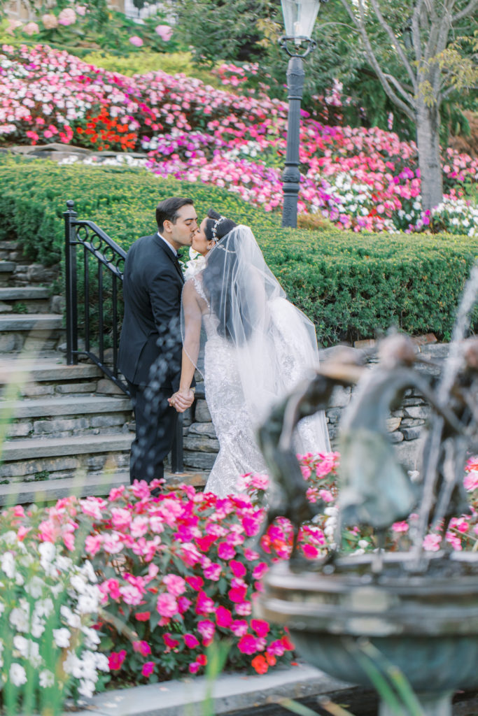 bride and groom kiss while walking through the garden