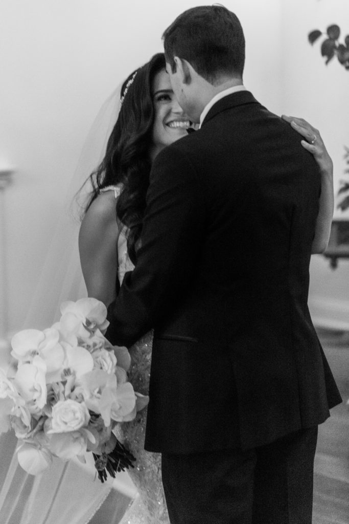 bride smiles at groom in wedding chapel in black and white
