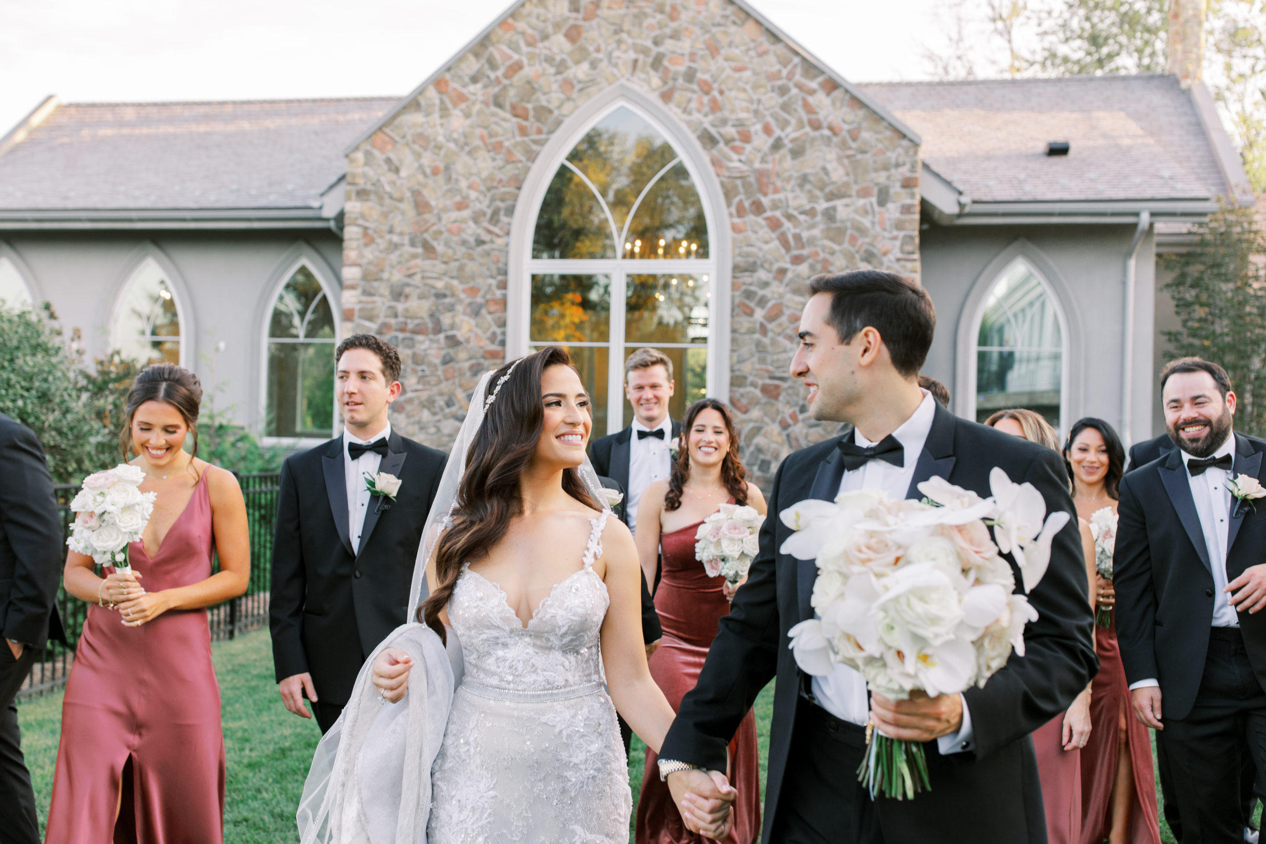 bride and groom smile at each other while walking with bridesmaids and groomsmen - Park Savoy Wedding Photography