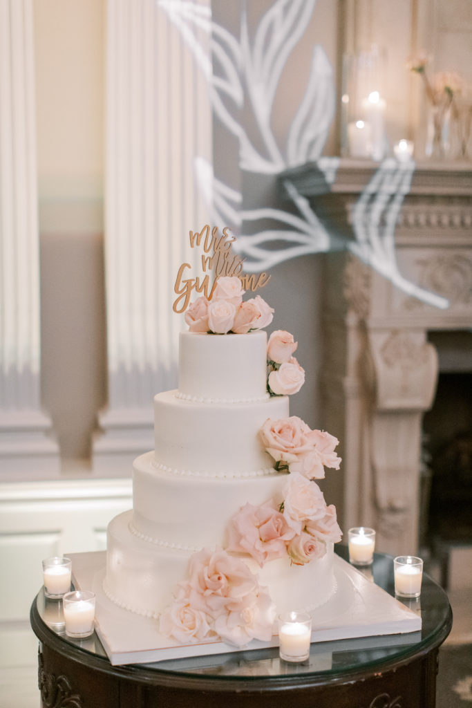 white wedding cake with blush roses and candles