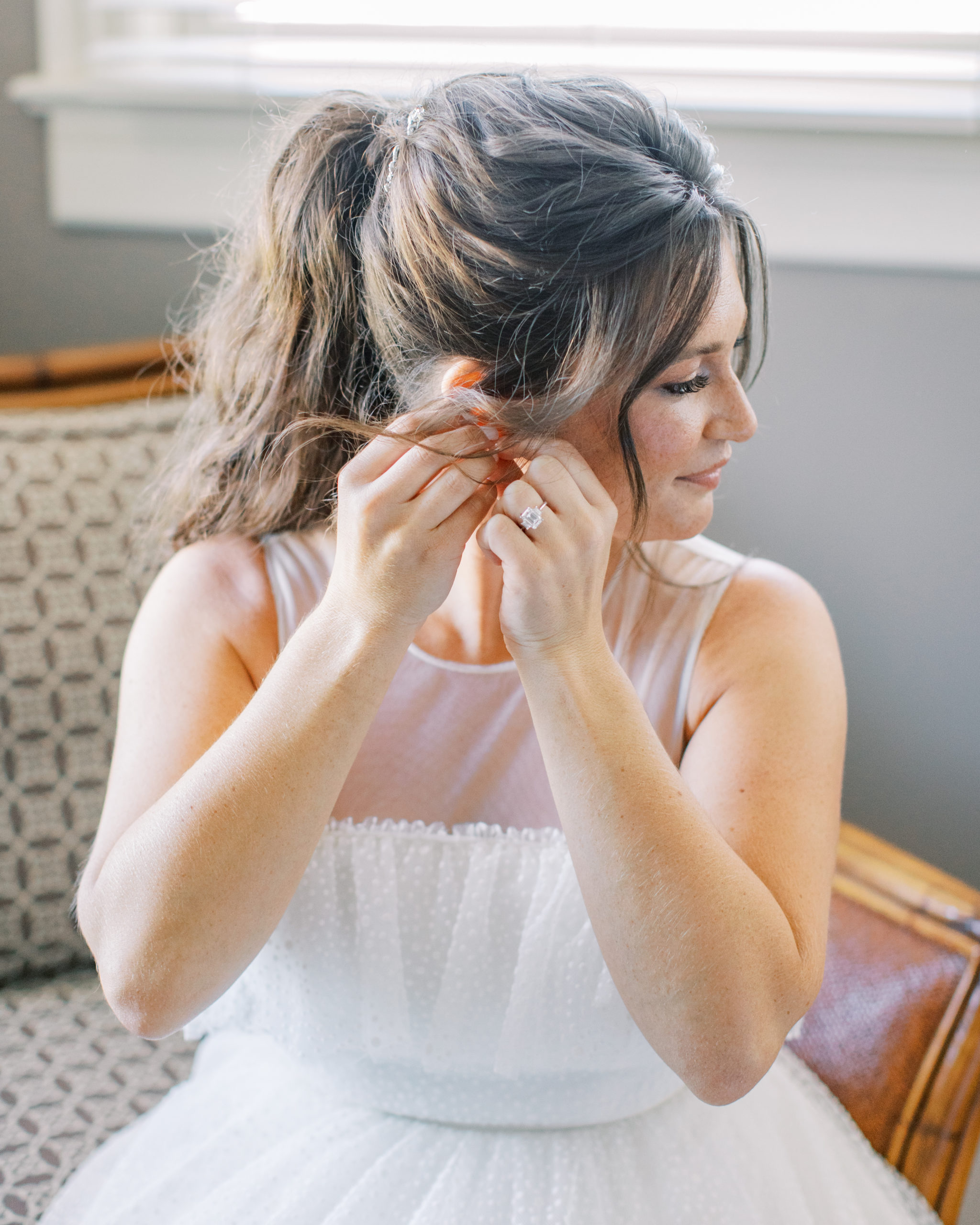 bride puts earring in while sitting in tan chair NJ Private Estate Wedding Photography