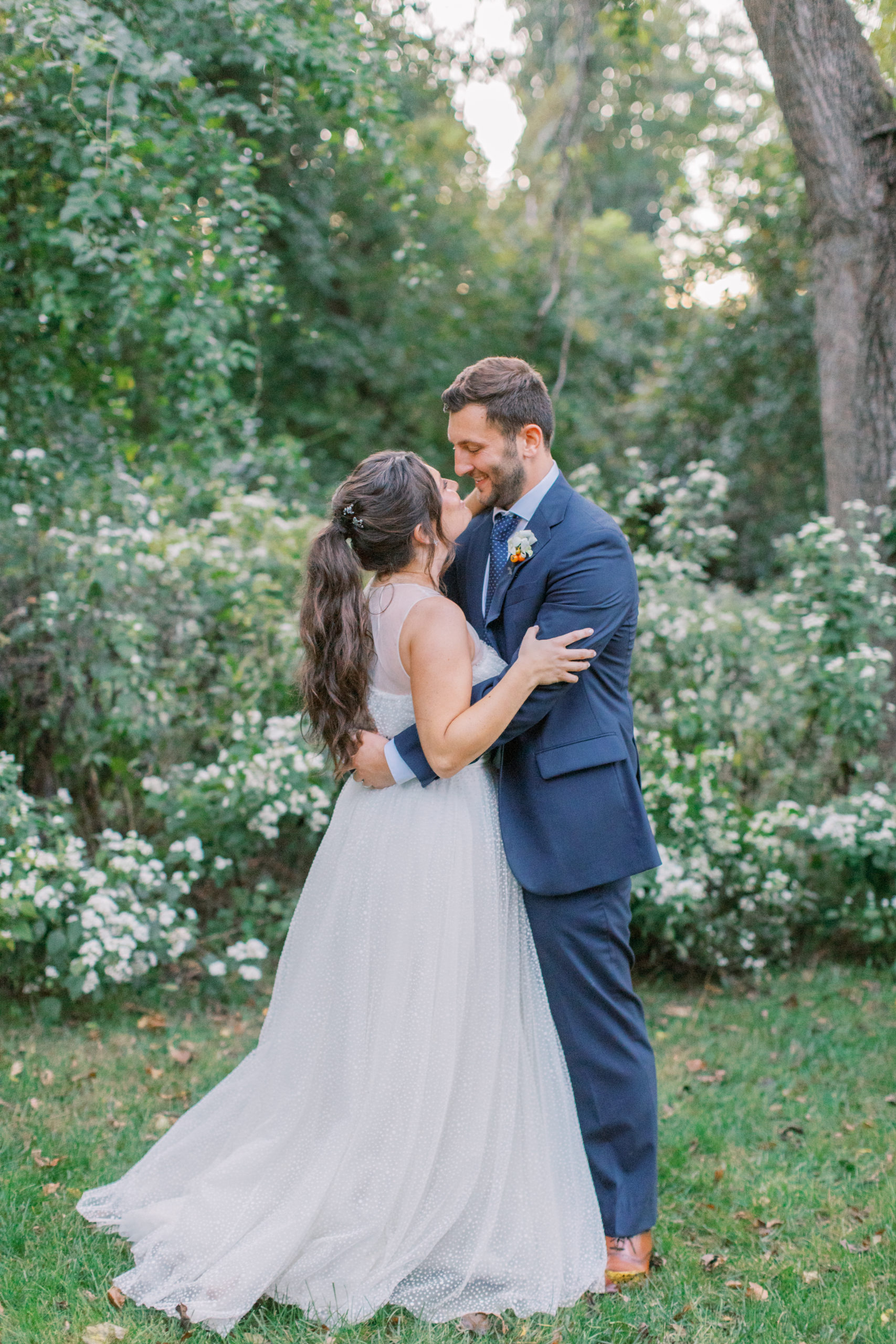 bride and groom smile at each other amid flowering bushes NJ Private Estate Wedding Photography