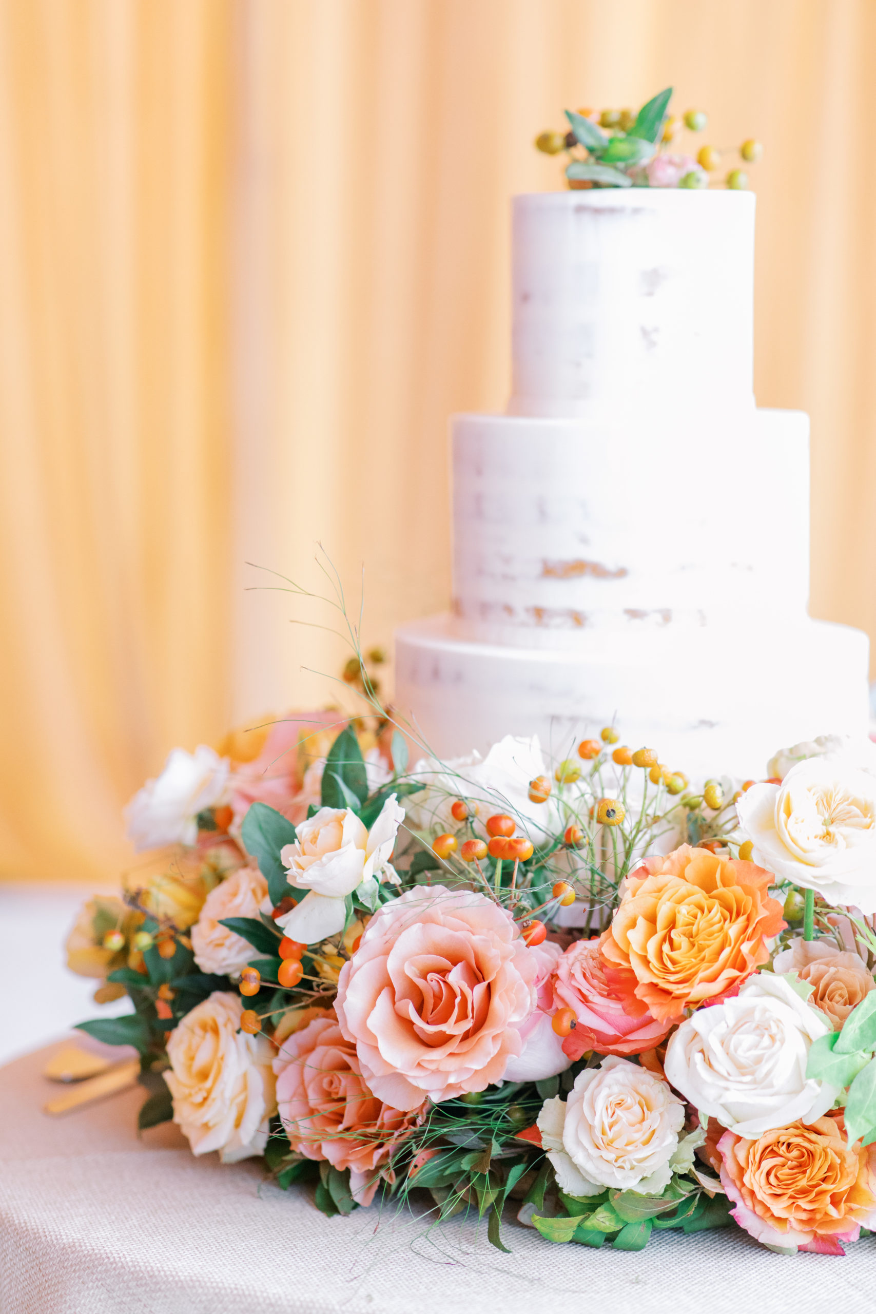 three tier wedding cake surrounded by blush and peach roses NJ Private Estate Wedding Photography