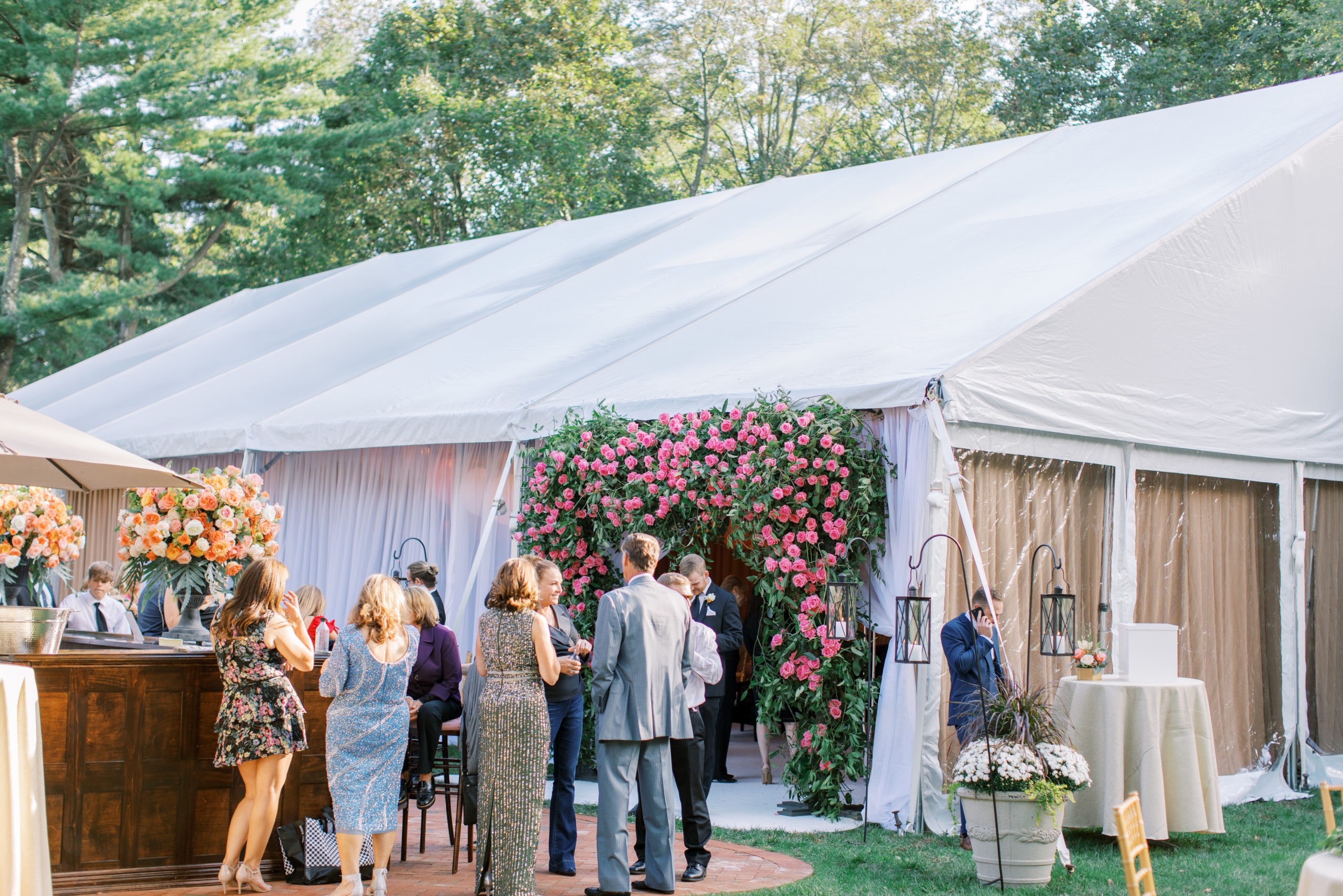 guests mingle during cocktail hour in front of rose covered arch NJ Private Estate Wedding Photography