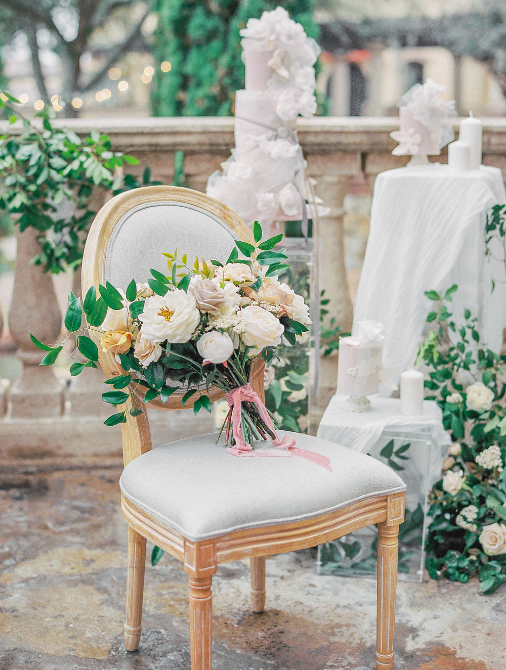 bridal bouquet on french chair with three luxurious wedding cakes and florals Bella Collina Wedding