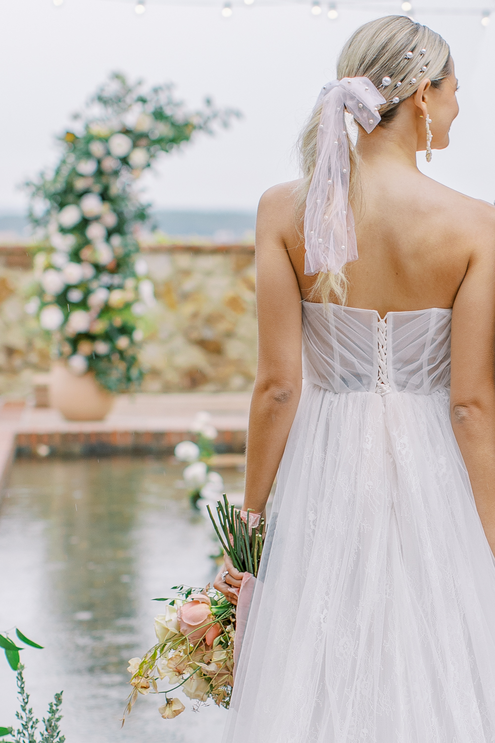 bride stands in front of reflecting pool holding bouquet