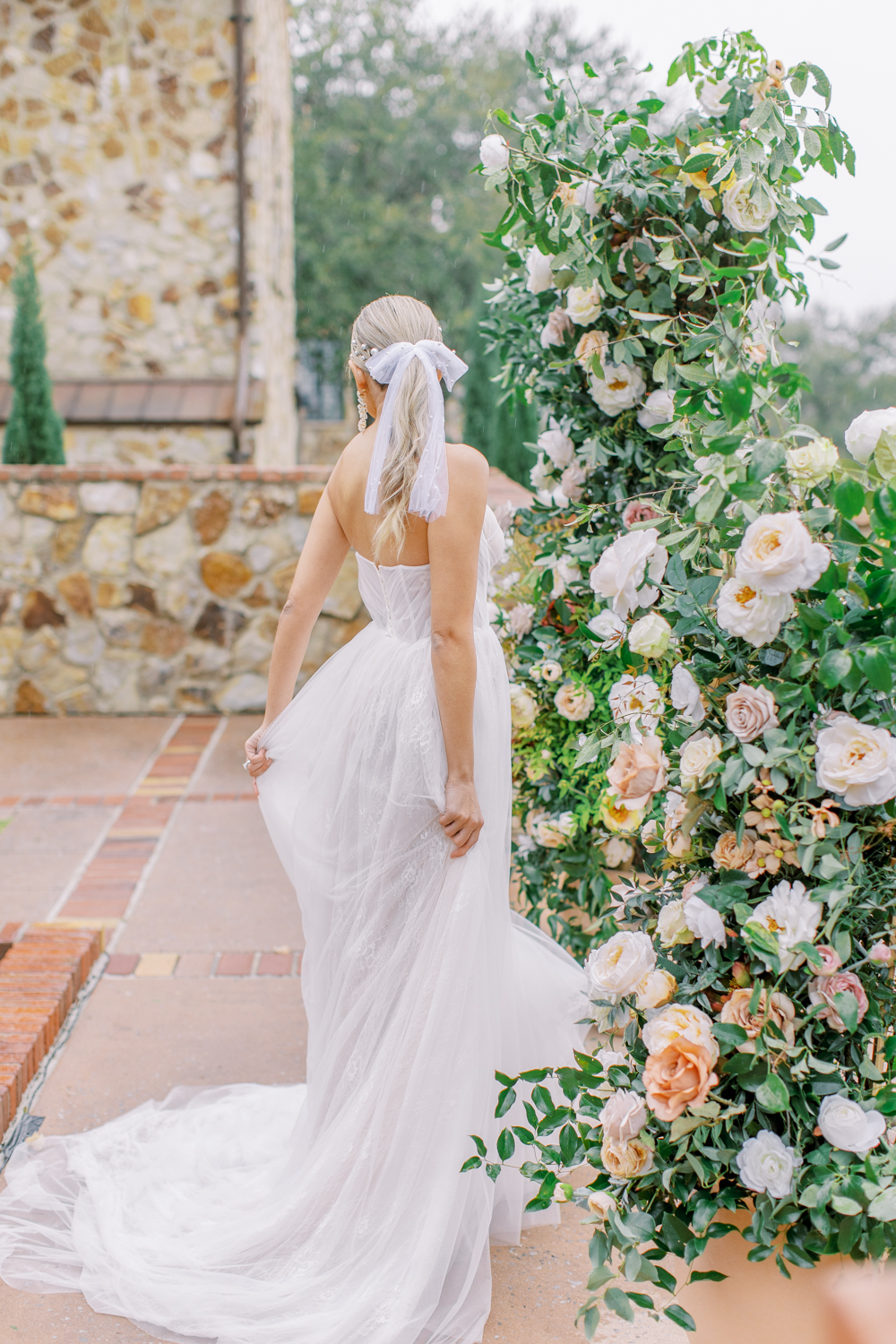 bride twirls in front of floral arch on rainy day Bella Collina Wedding