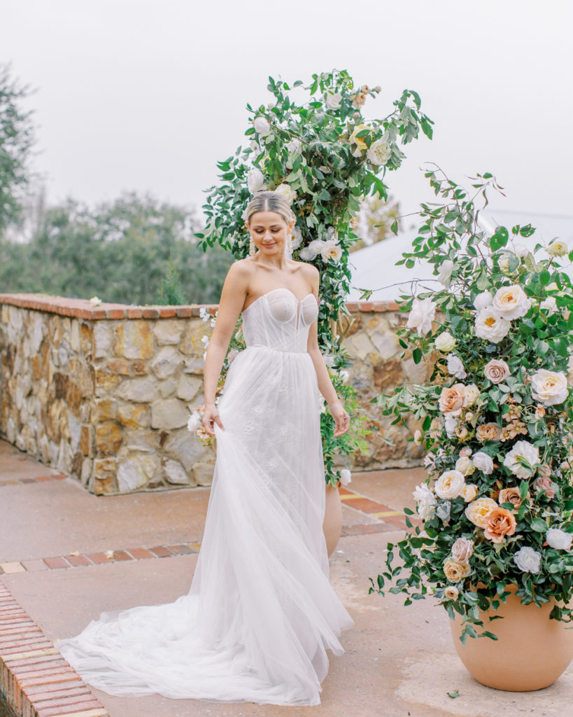 bride twirls joyfully in front of rose arch on italian stone terrace