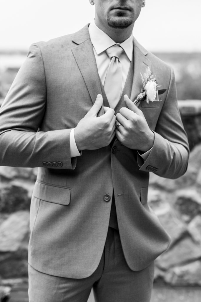 groom holds suit jacket in black and white