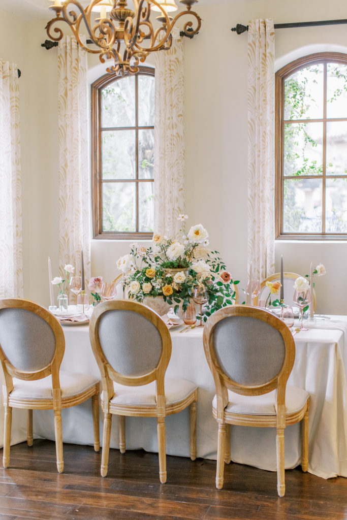 wedding reception table with french chairs and rose centerpieces