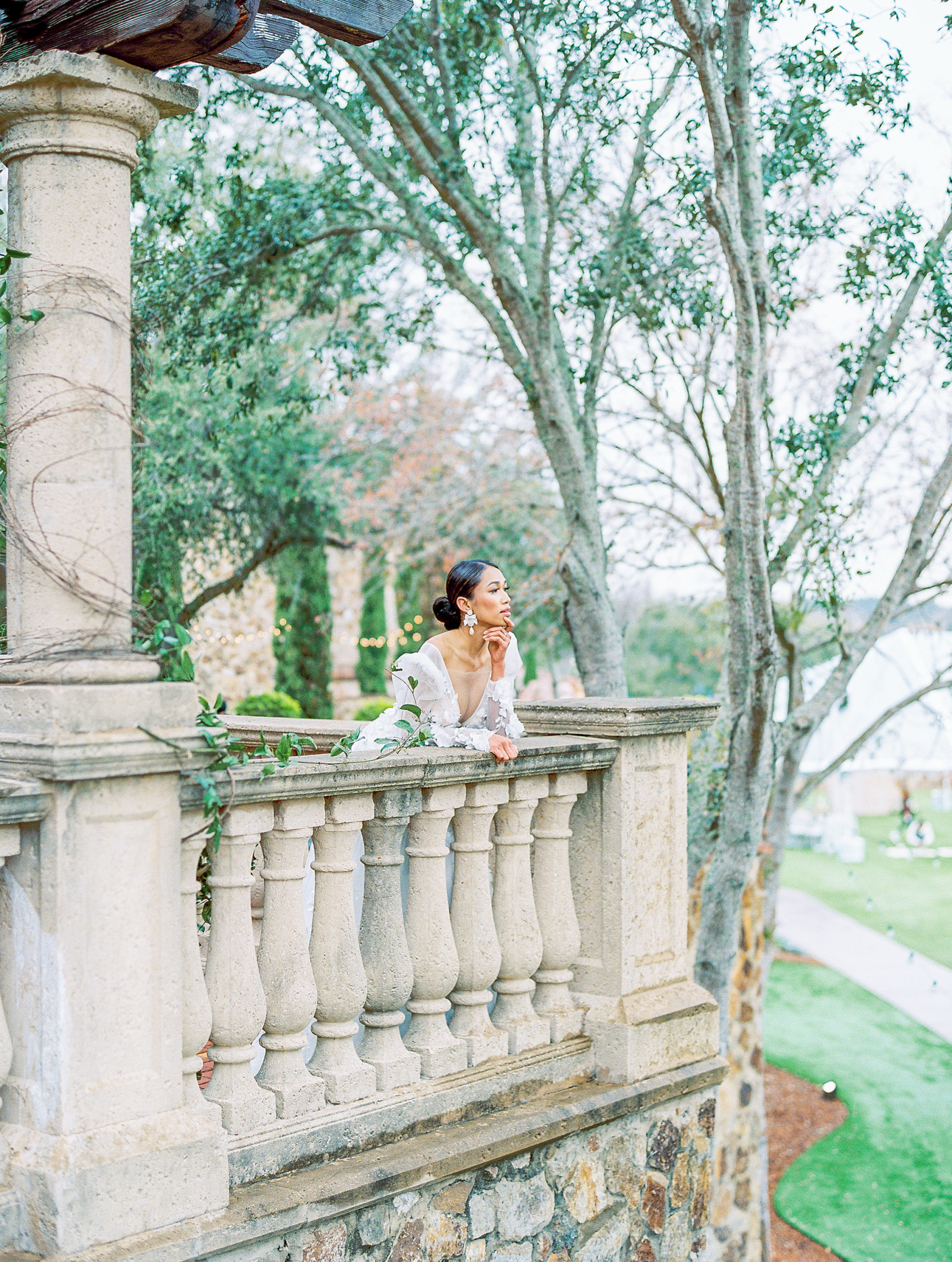 bride looks out over stone terrace overlooking green grounds Bella Collina Wedding Photography