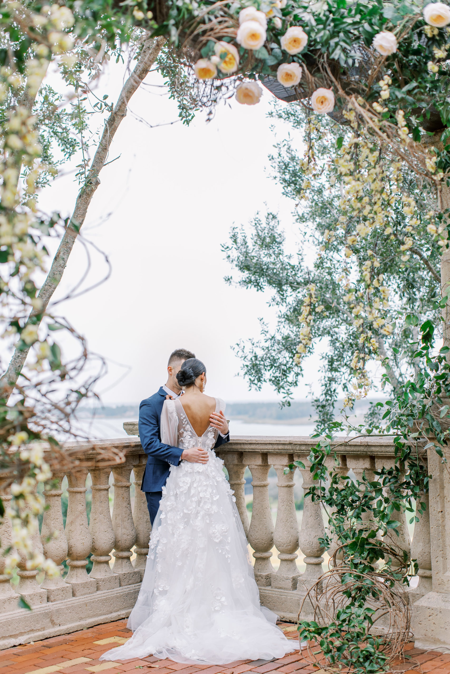 bride and groom embrace surrounded by roses and climbing floral vines Bella Collina Wedding Photography