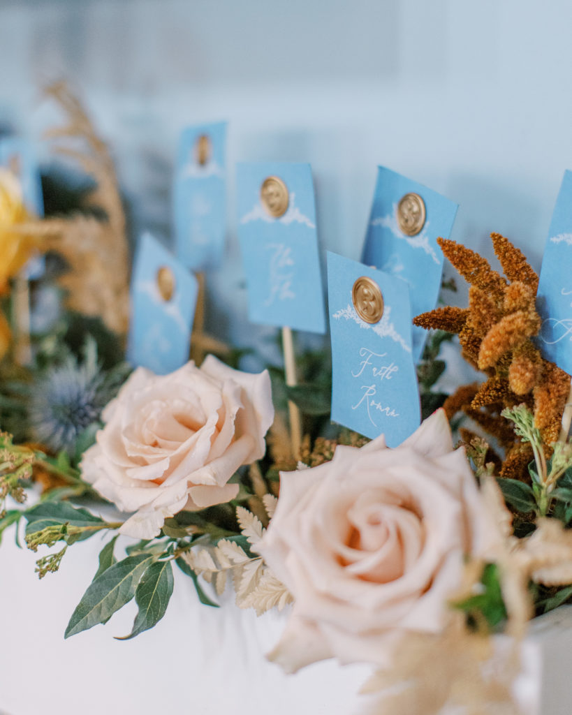 close up of seating assignment cards with blush roses and a blue background