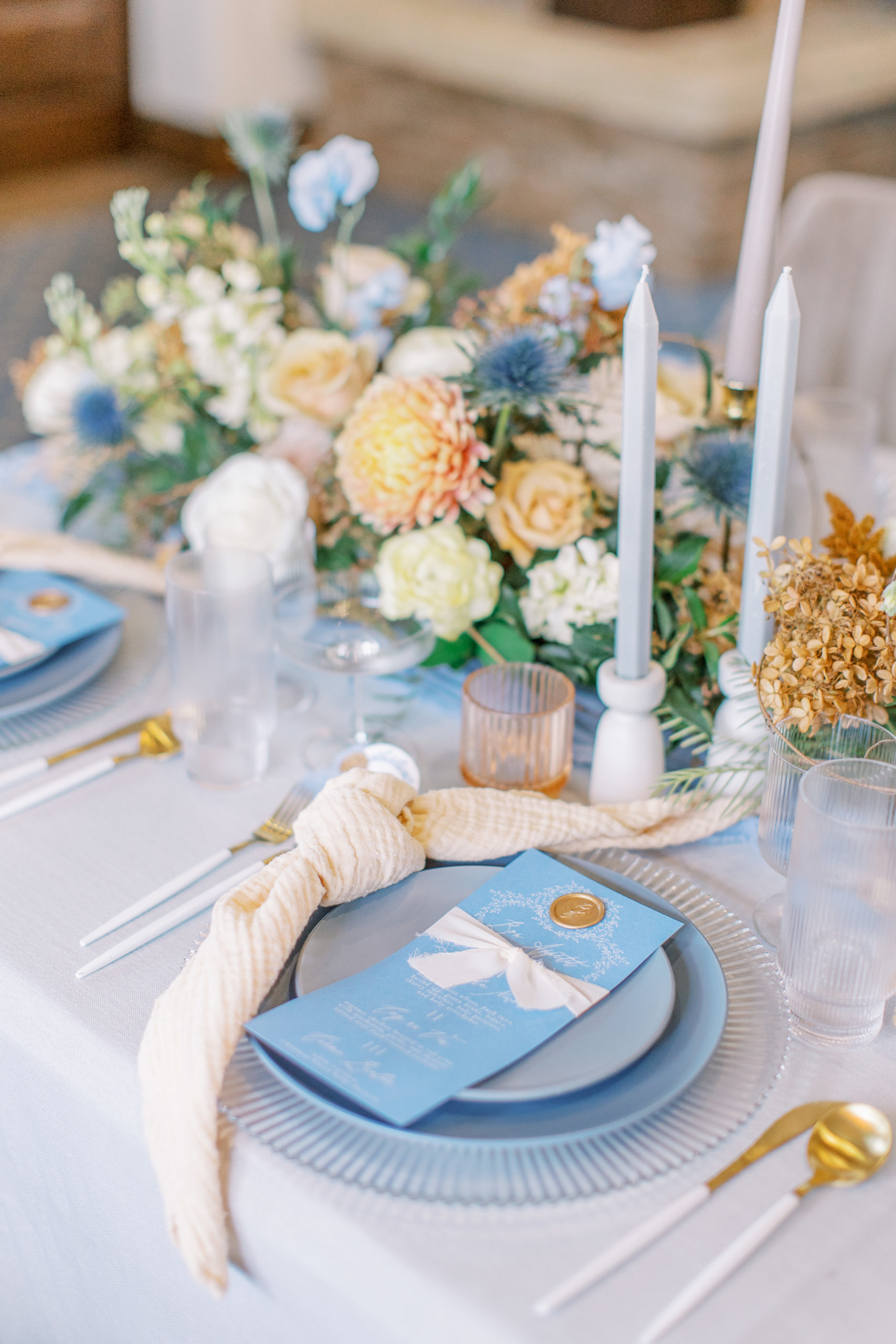 wedding reception table setting with blue menu cards and abundant florals