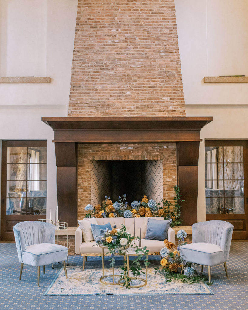 wedding lounge set with blue chairs and large stone fireplace