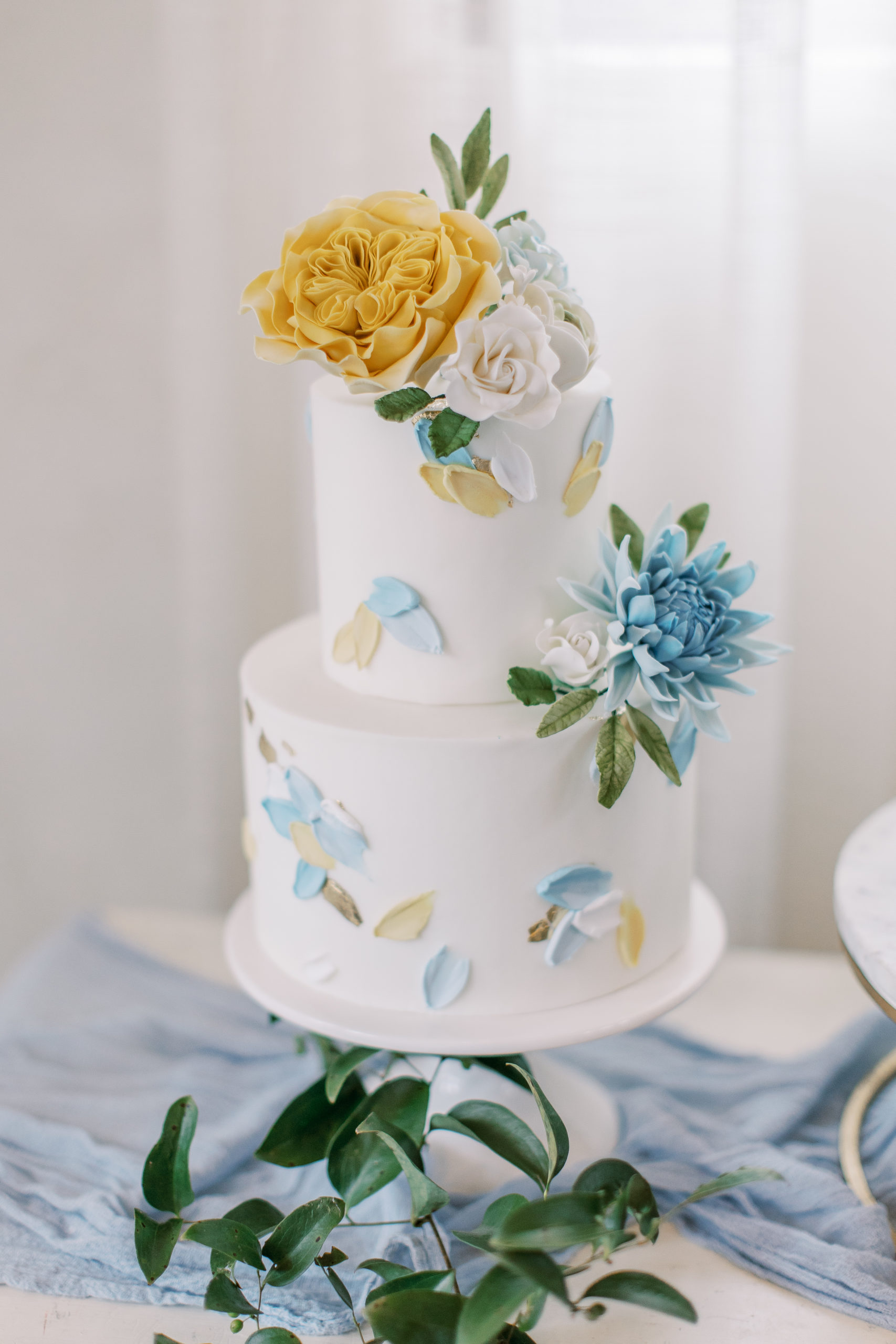 White wedding cake with blue and gold brush strokes and flowers