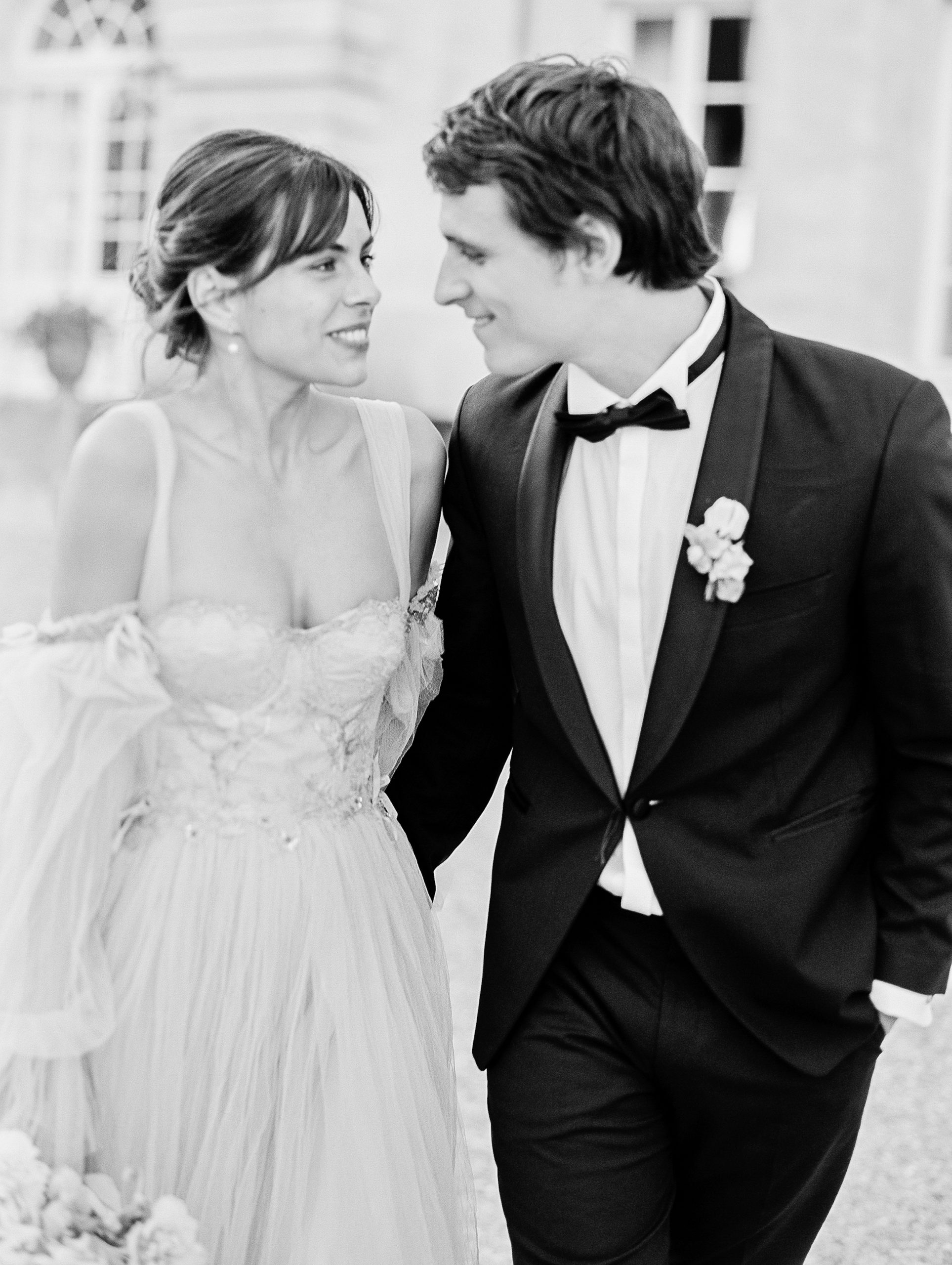 Bride and groom smile at each other in black and white