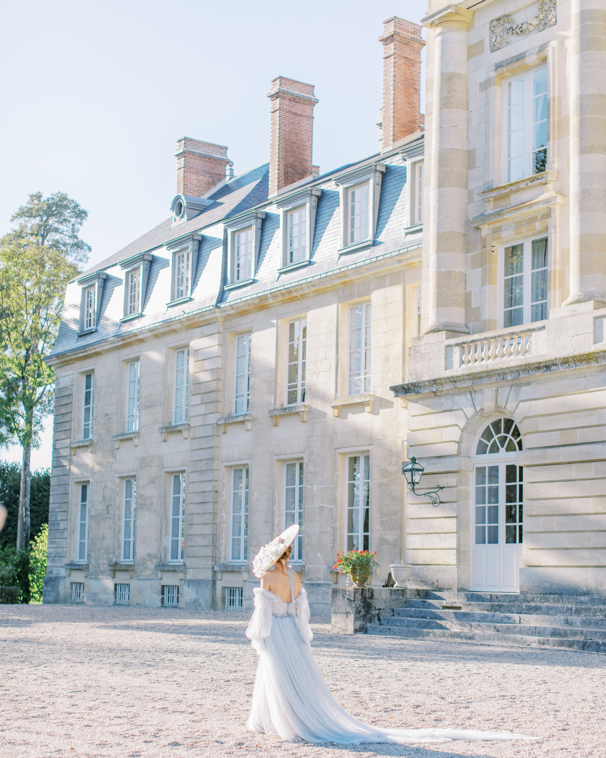 Bride in Floral Hat walks at French Chateau Wedding