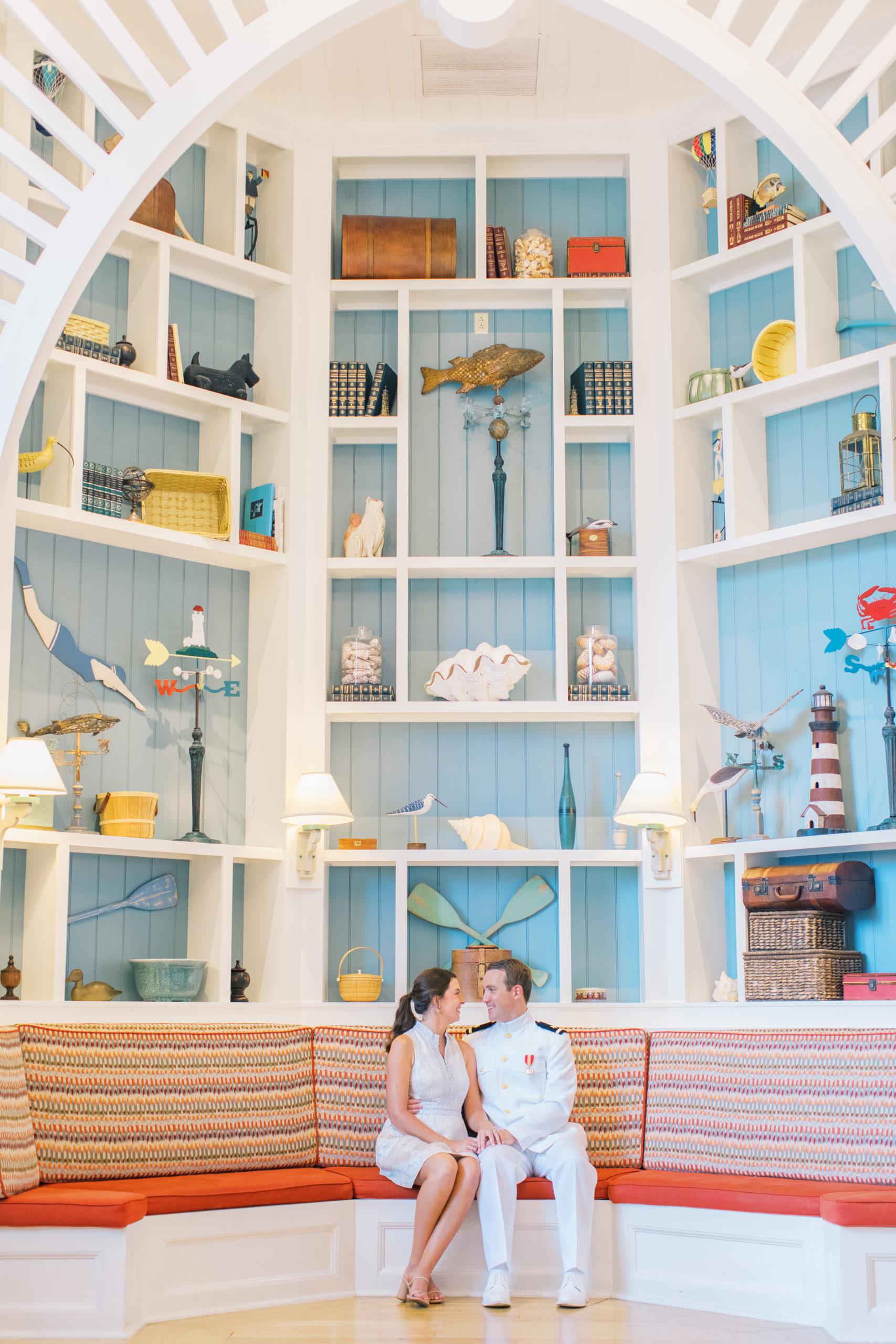 Couple smiles at each other seated in front of large bookcase at Disney's Boardwalk Engagement Session