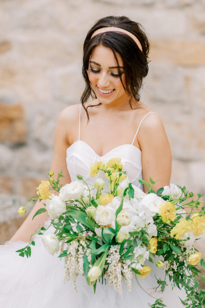 bride smiles at her bouquet at italian villa Sunstone Winery Wedding Photography