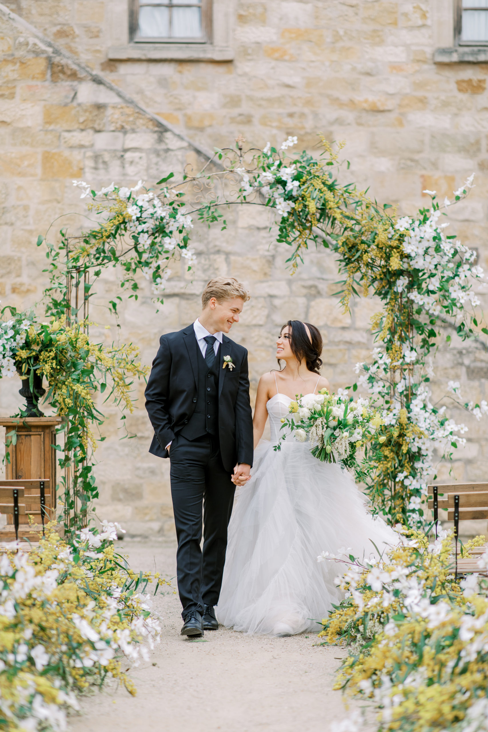 bride and groom walk down flower lined aisle at italian villa wedding Sunstone Winery Wedding Photography