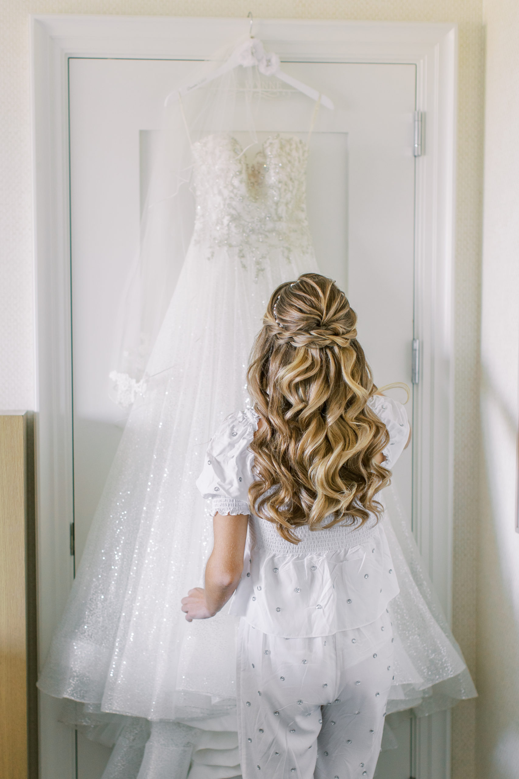 Beautiful bride with long blonde hair looks at her dress 

