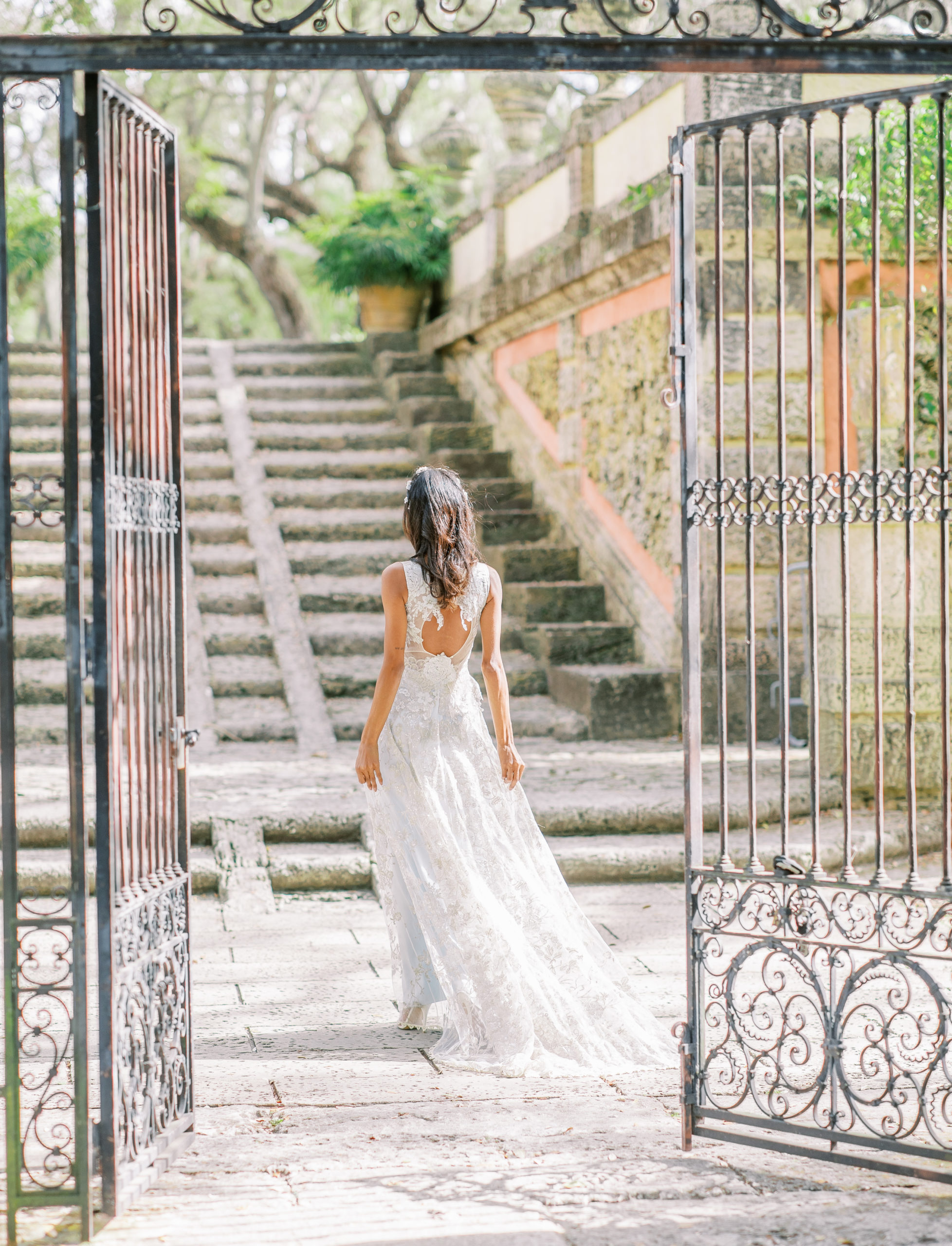 bride in couture dress walks through iron gate towards stone steps