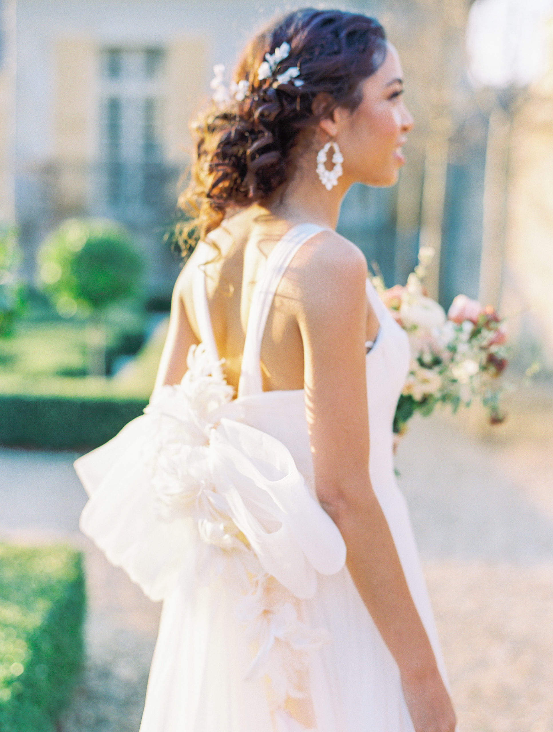Bride looking away with cream earrings and flowers in hair at Chateau de Villette Wedding Photography