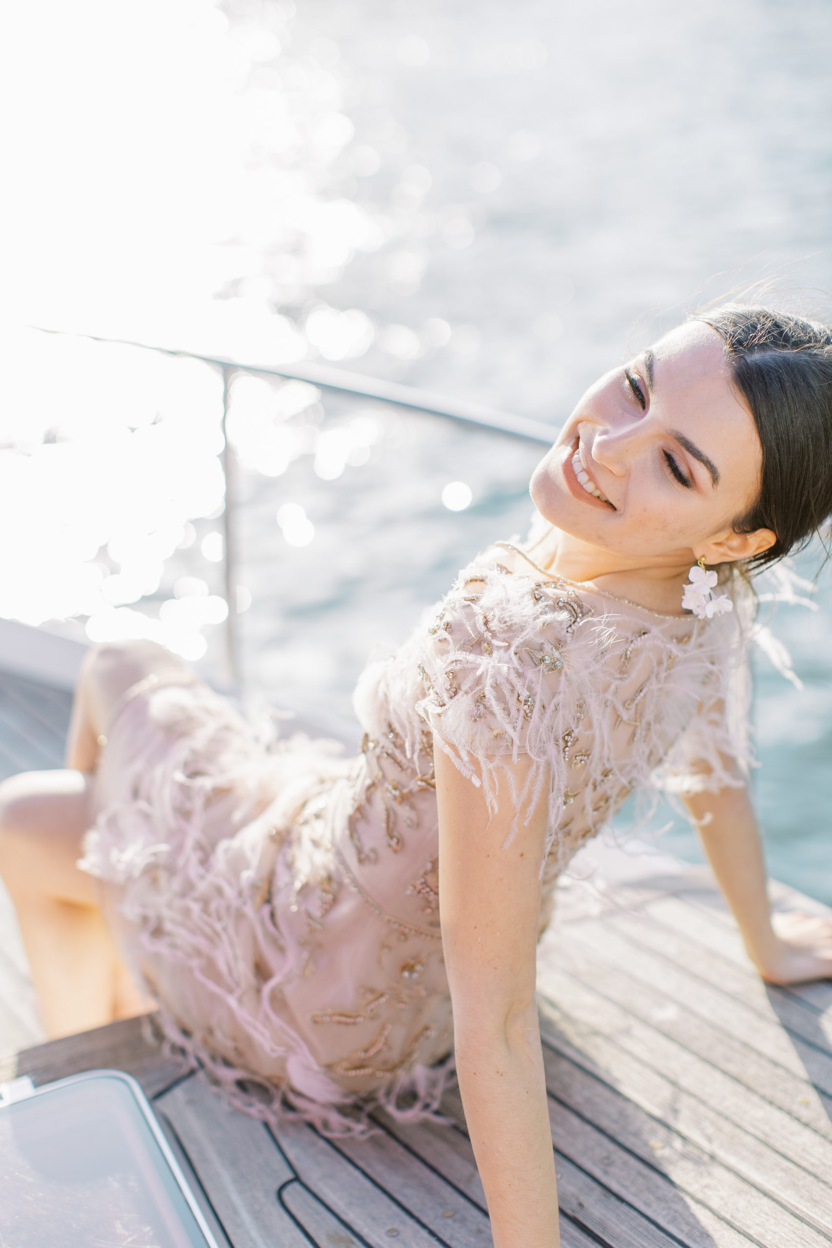 Bride sitting on boat smiling in pink dress for Sunset Paris Engagement 
