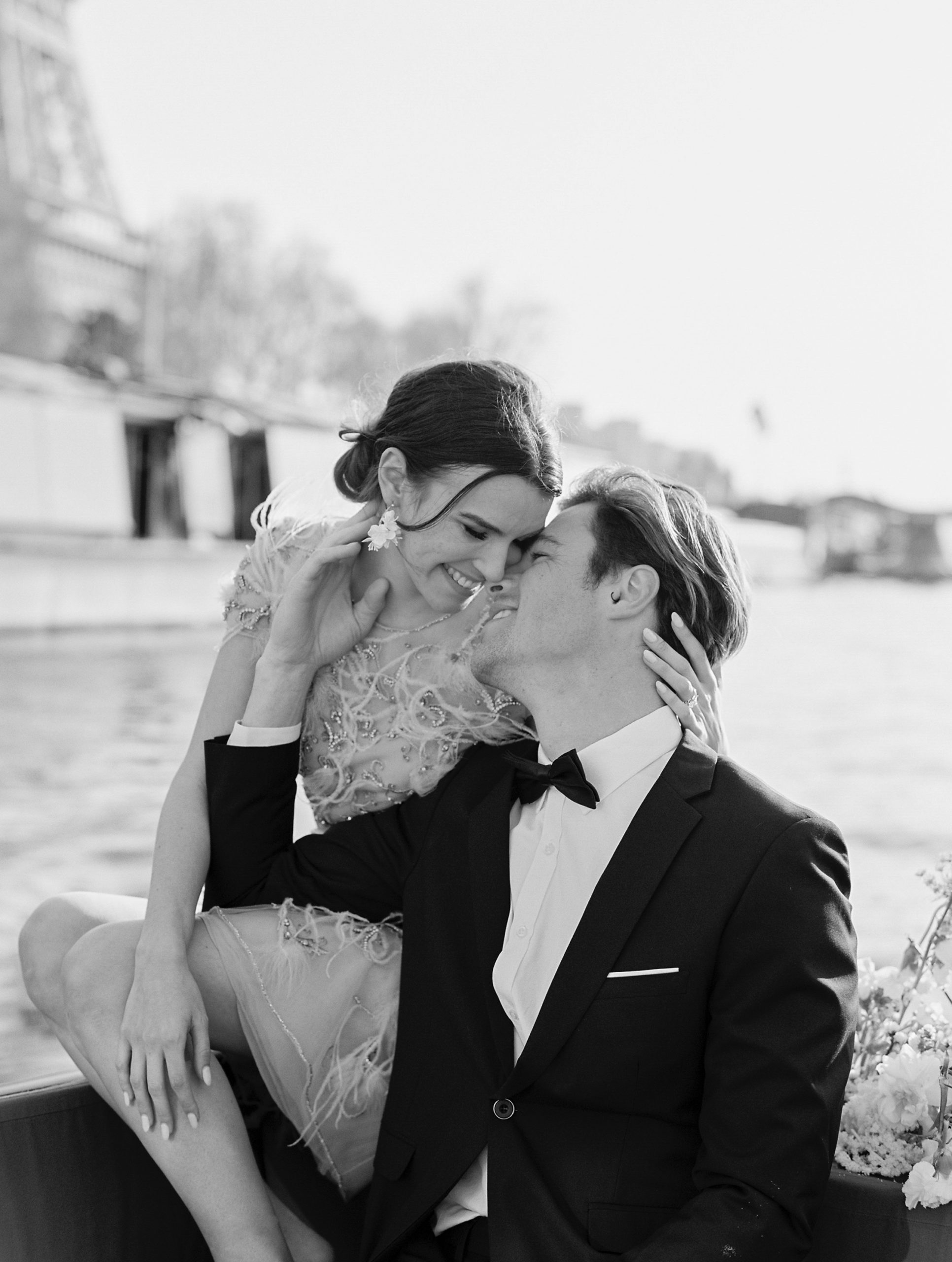 Couple leaning in for a kiss in a boat on the river for Sunset Paris Engagement 