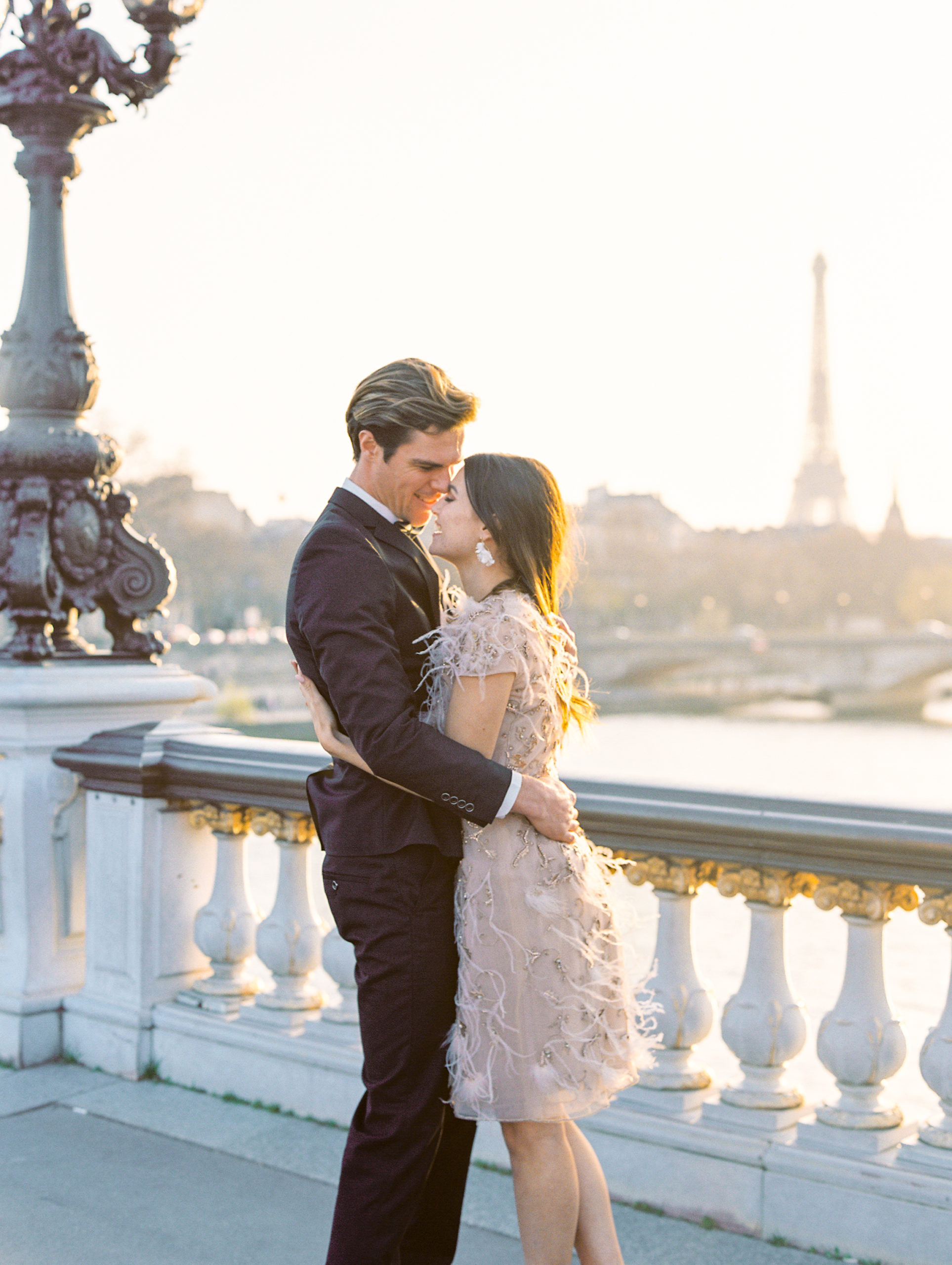 Couple embracing on bridge with Eiffel towel in background 