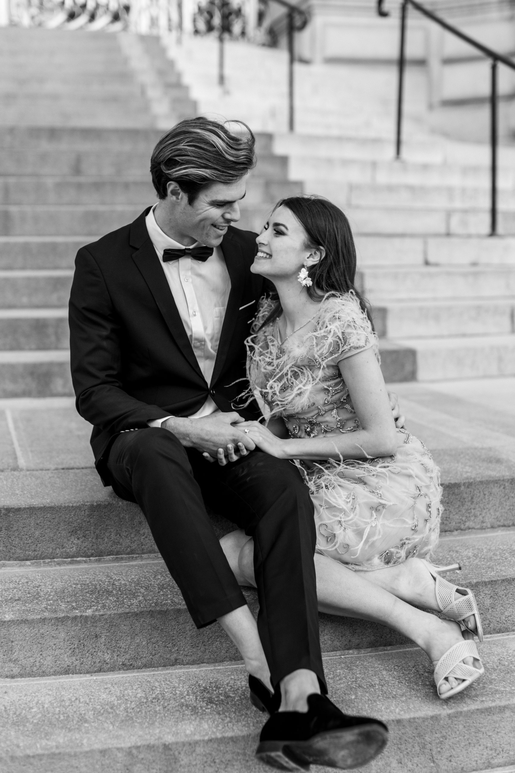 Couple sitting on steps smiling and holding hands 