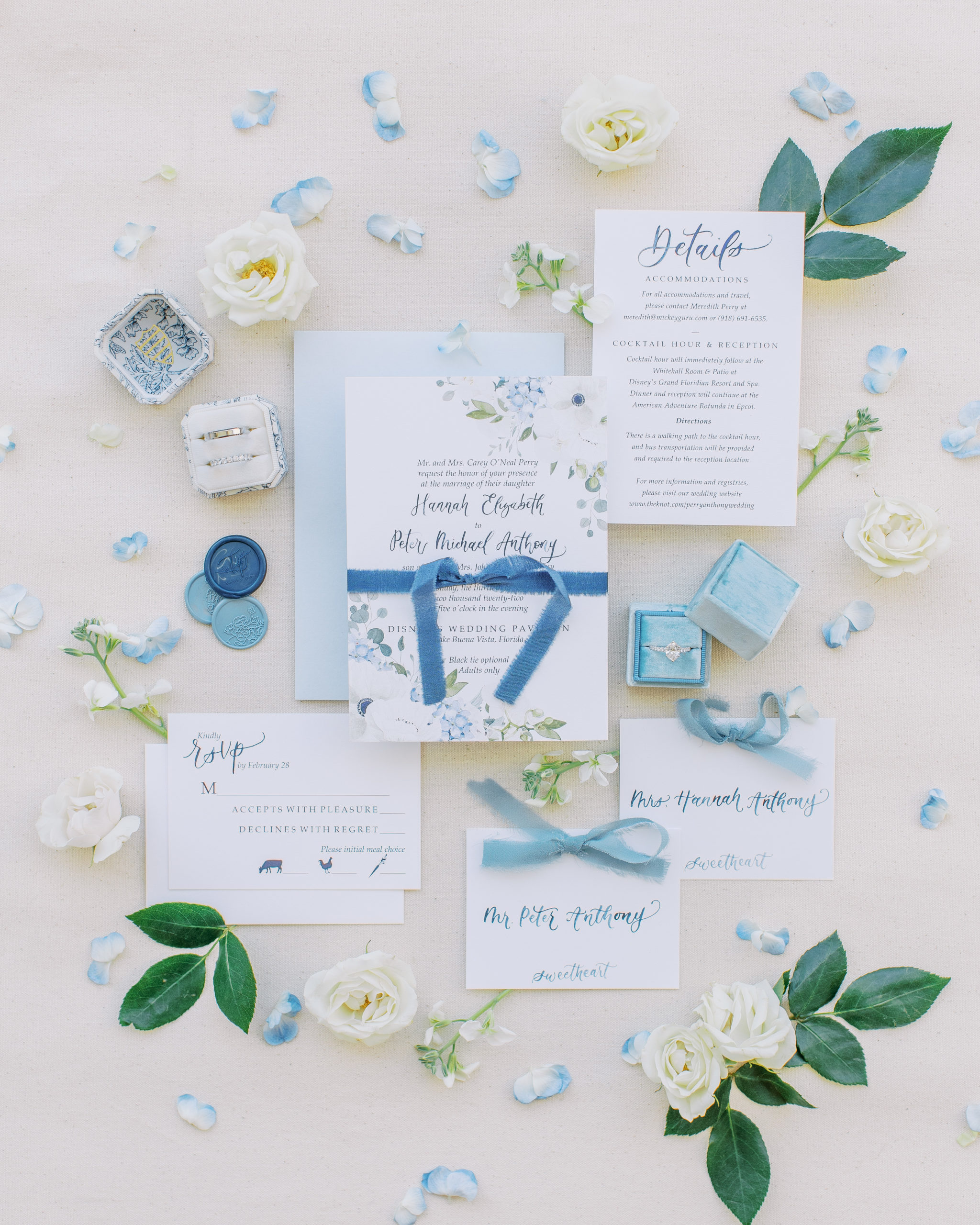 Light blue invitations with white and blue flowers and petals with ring boxes for a Romantic and Timeless Grand Floridian Wedding 