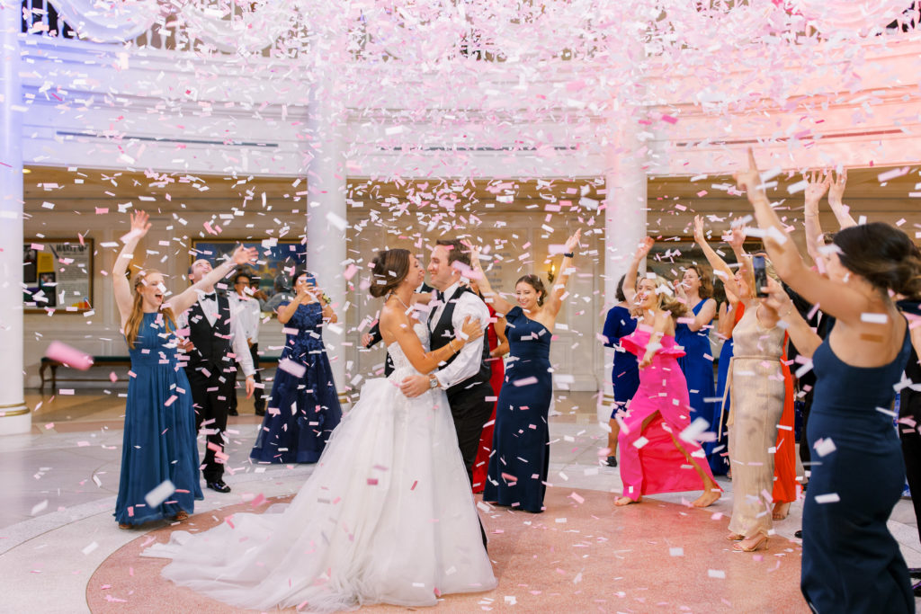 Wedding reception with guests dancing and bride and groom. Pink confetti falls on the dance floor at a Romantic and Timeless Grand Floridian Wedding 