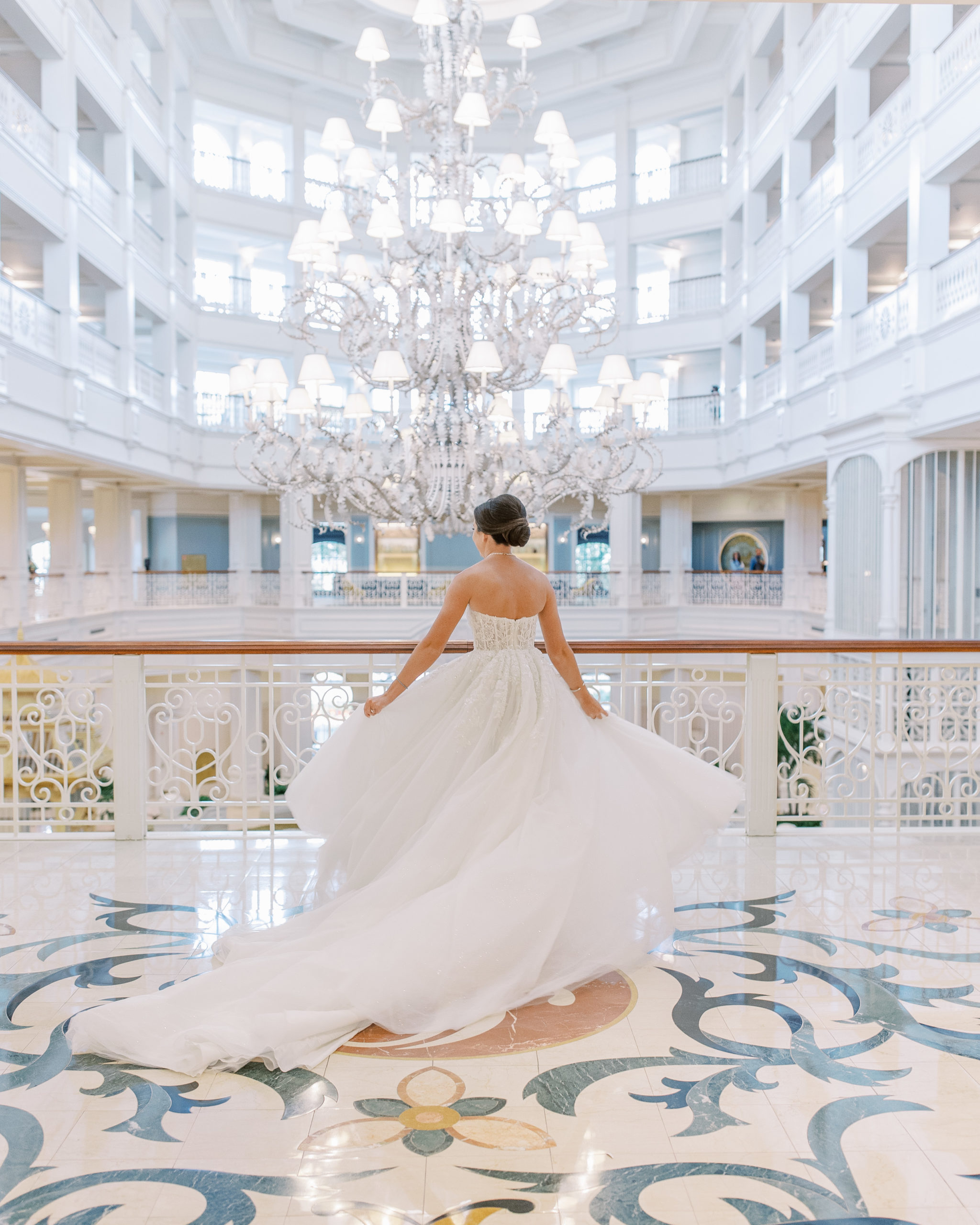 Bride spins her dress with large chandelier and balconies in the background at Disney's Resort for a Romantic and Timeless Grand Floridian Wedding   