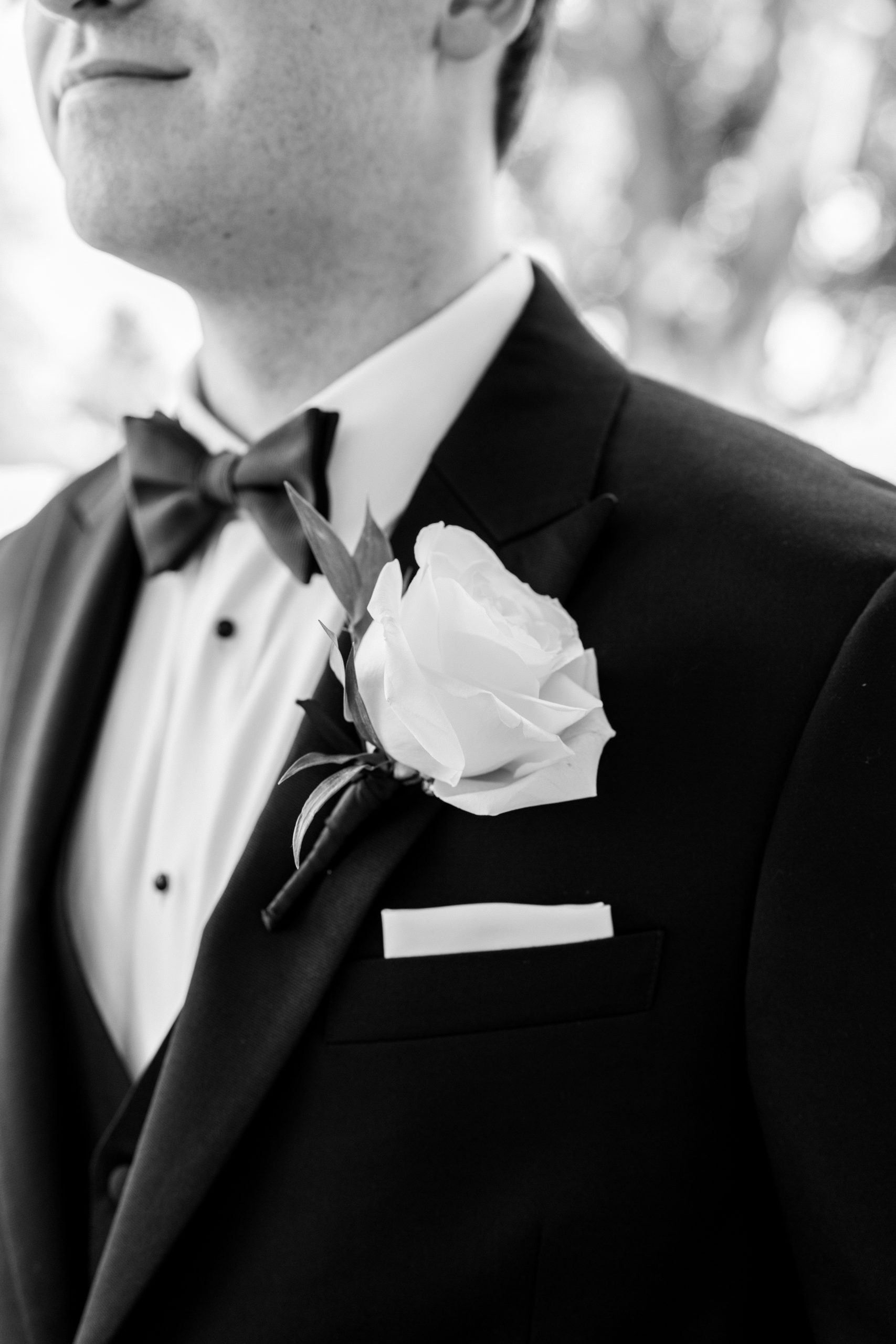 Up close view of groom's corsage and suit jacket in black and white 