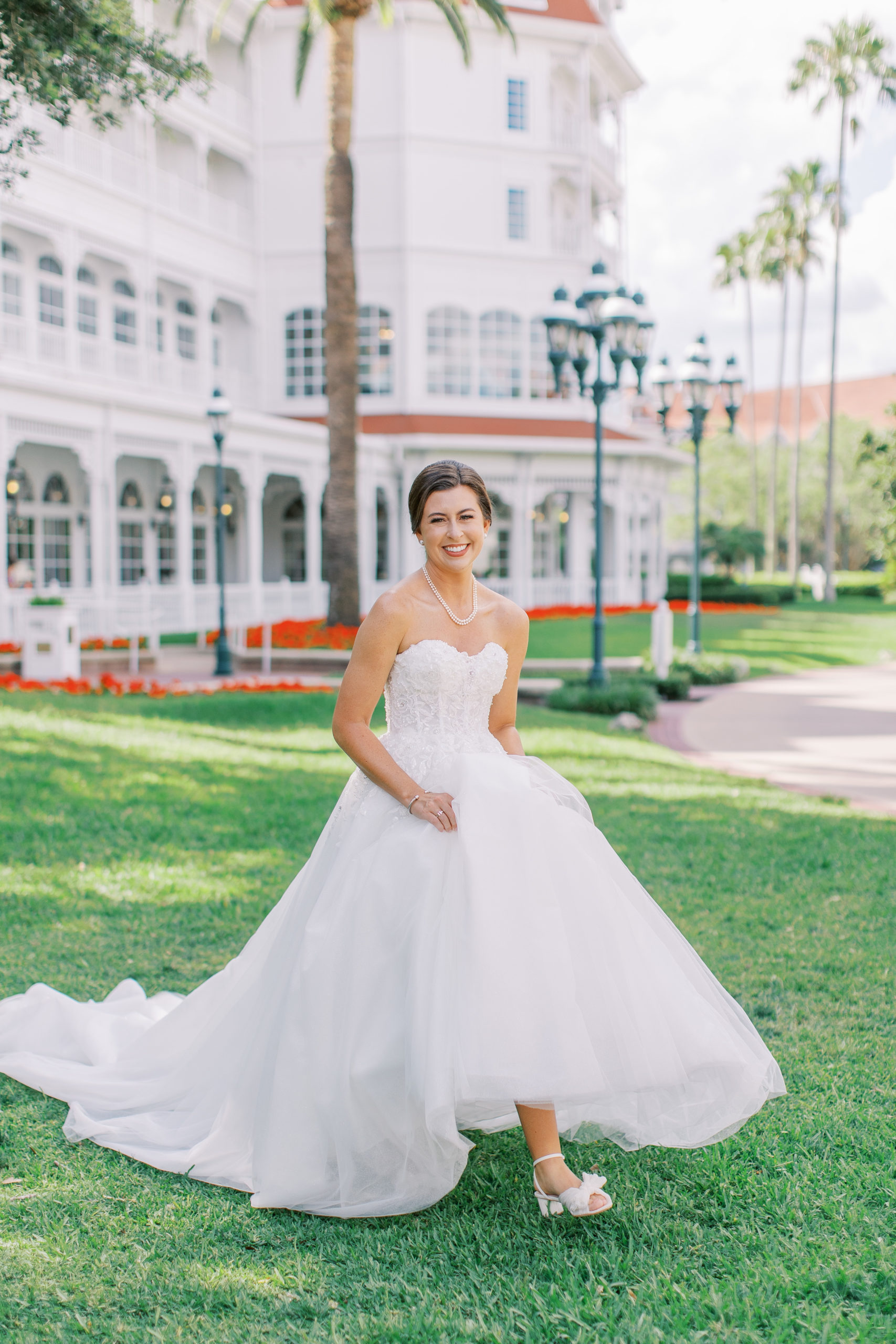 Bride smiling and walking in lawn in front of Disney's resort for a Romantic and Timeless Grand Floridian Wedding 