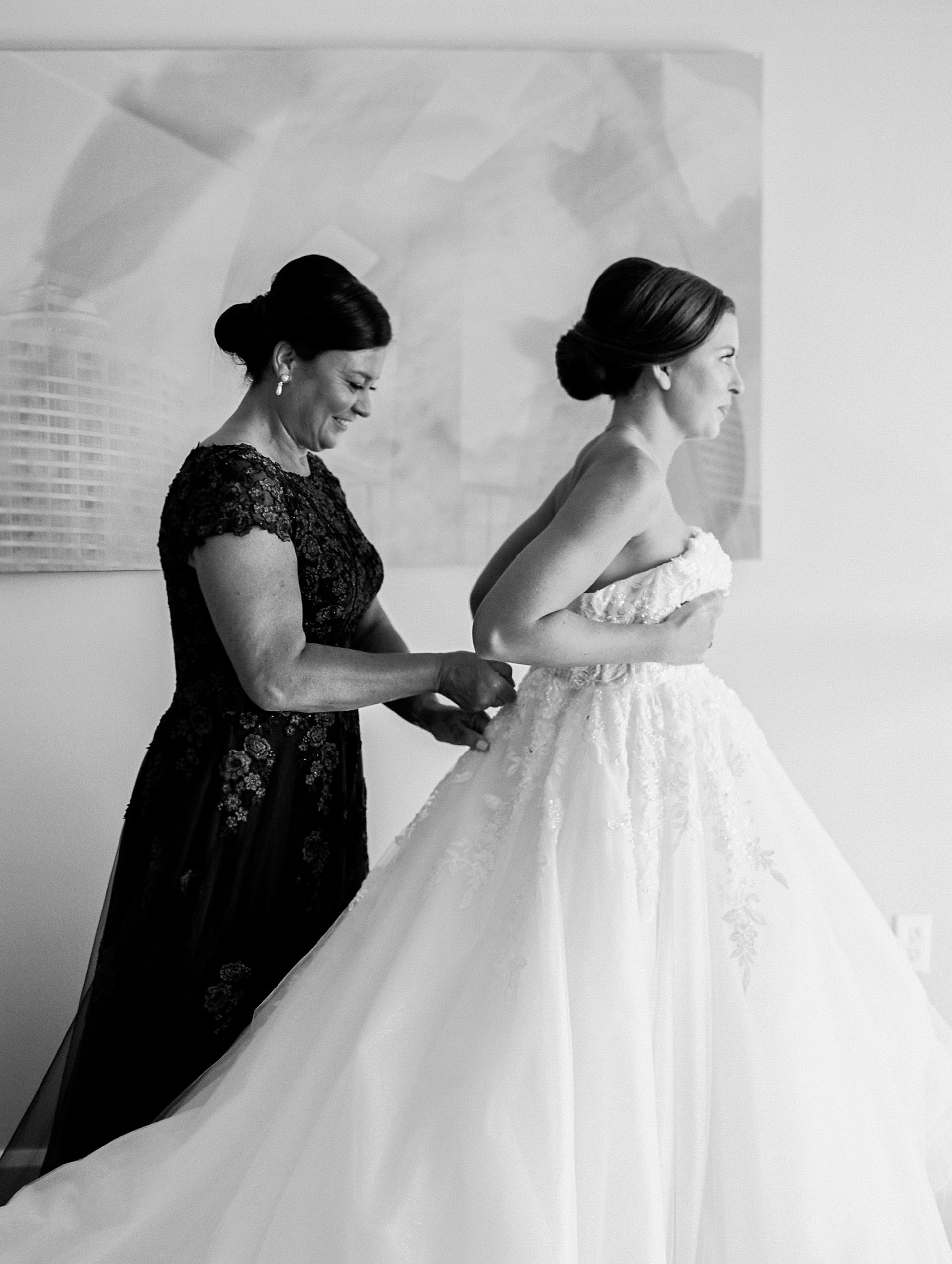 Mother of the bride helps daughter zip her dress at a Romantic and Timeless Grand Floridian Wedding 