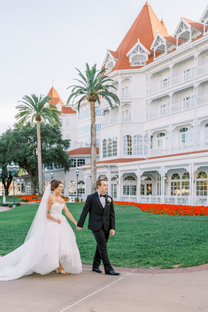 Bride and groom hold hands walking along path at Disney's Spa and Resort 