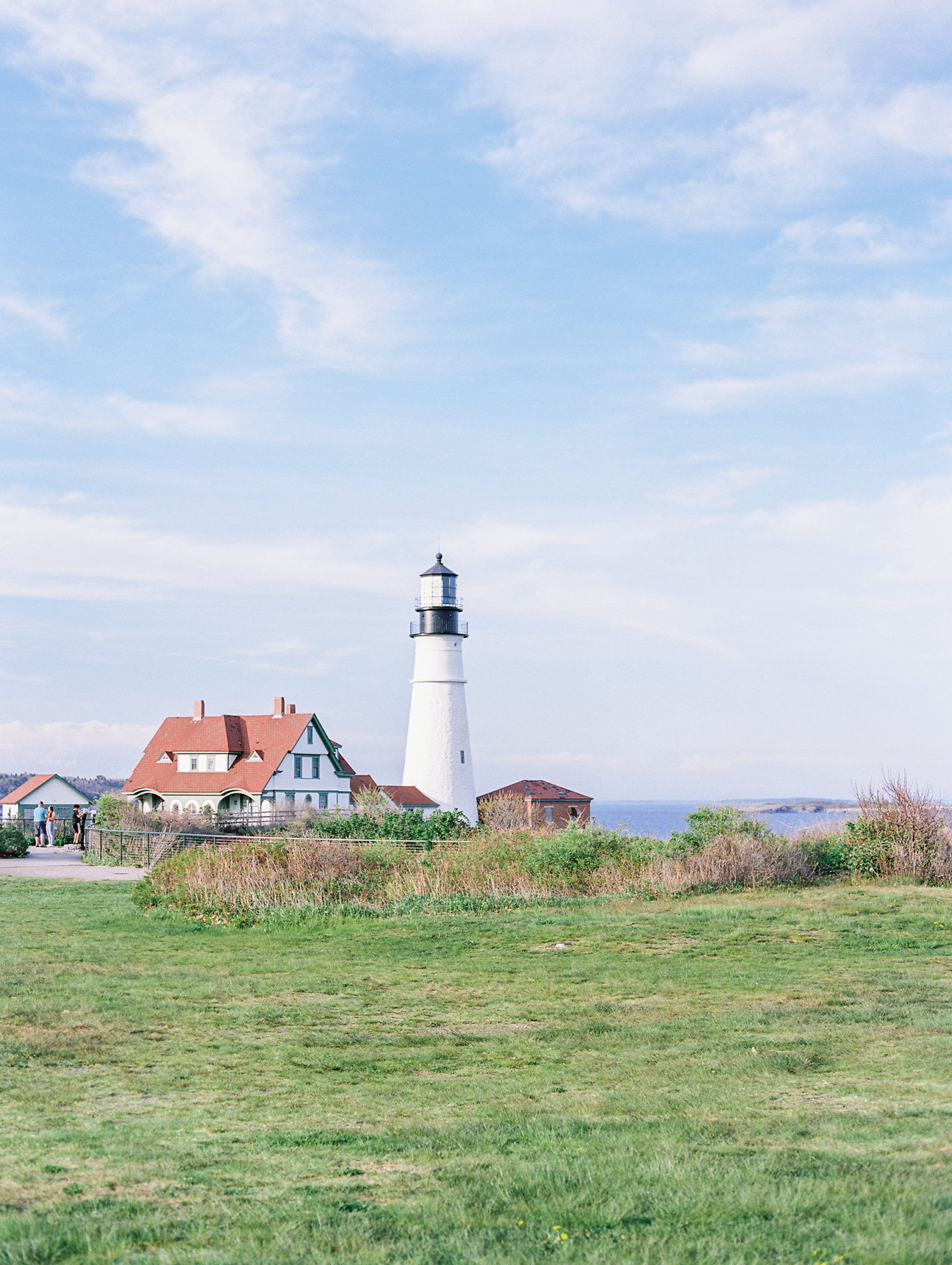Lighthouse overlooking field and dunes at Coastal Maine Engagement Session 