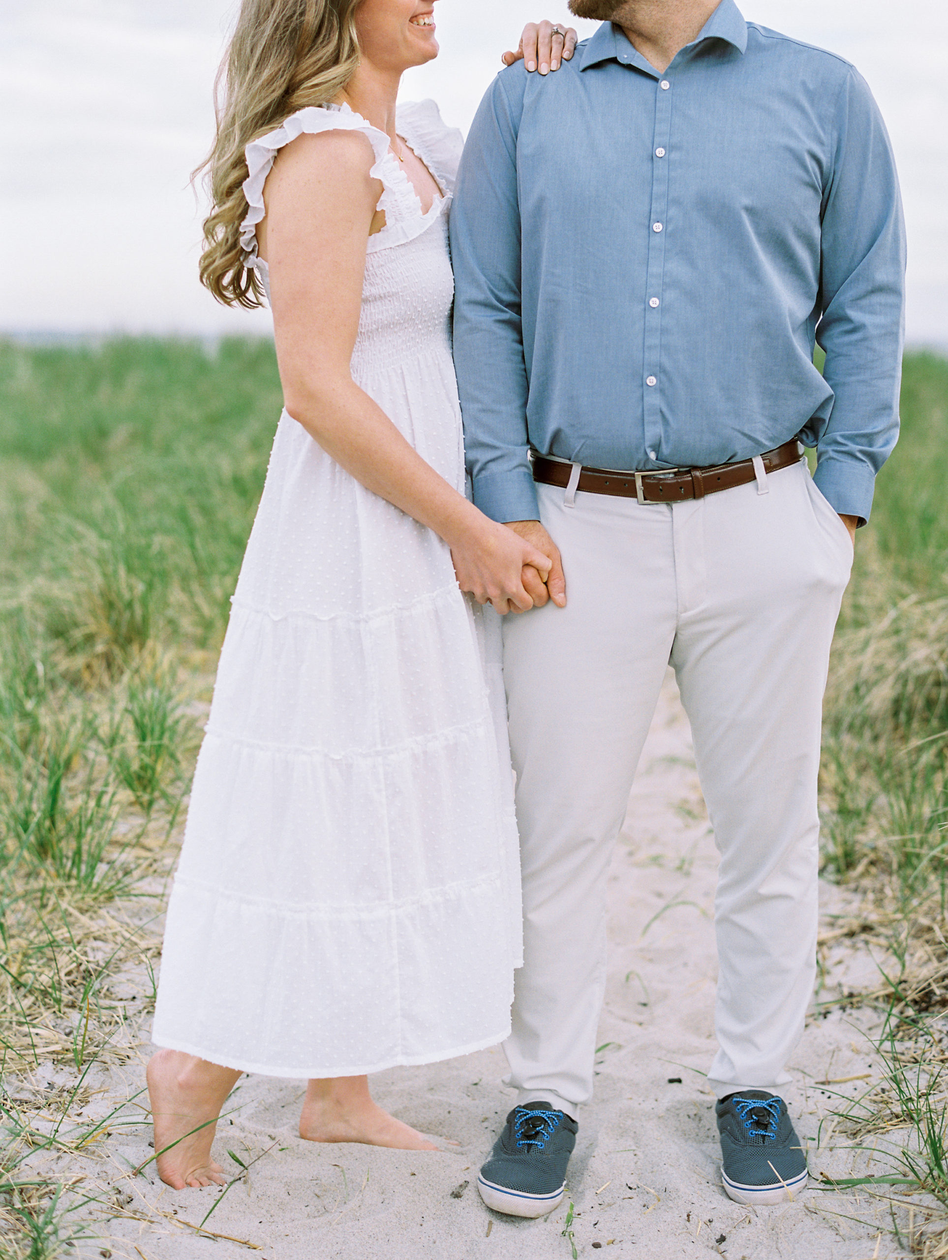 Couple holding hands on beach path for Coastal Maine Engagement Session