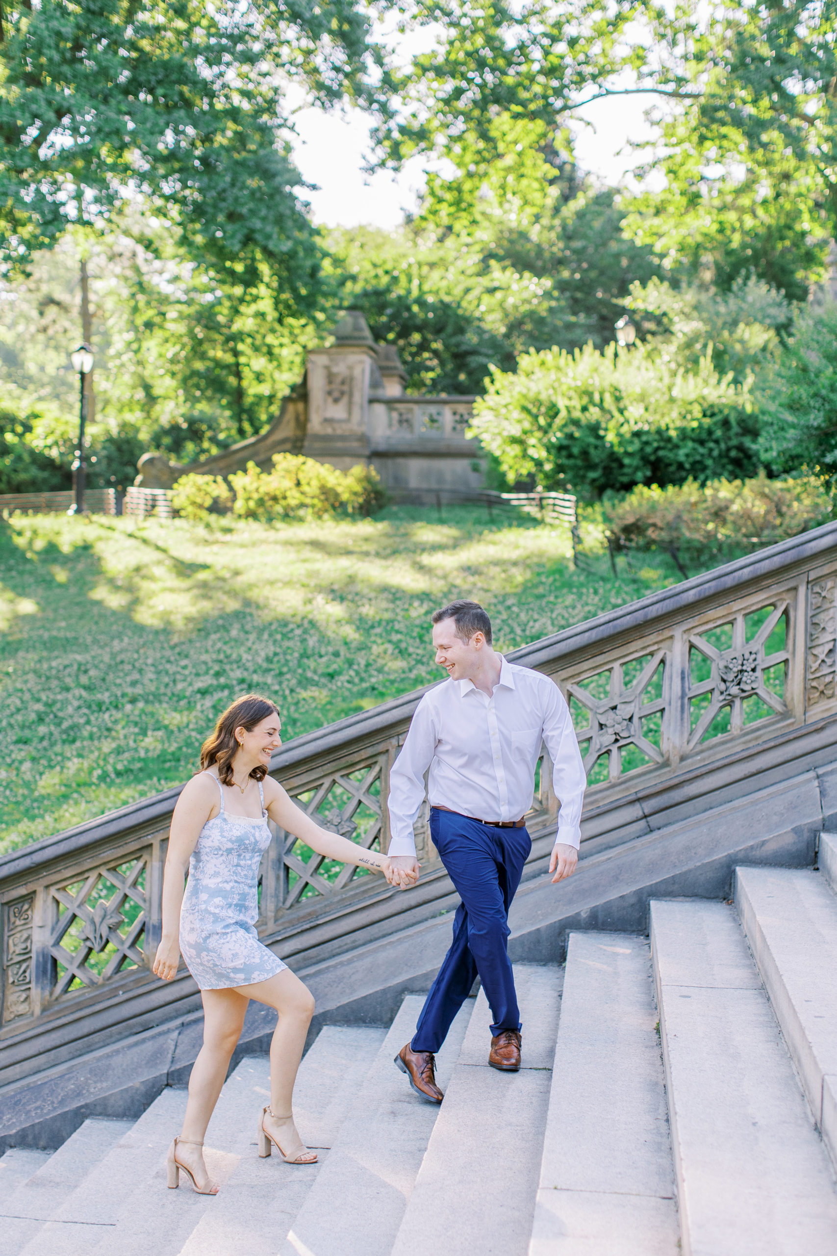 Couple smiling and holding hands walking up steps in Central Park for Central Park Engagement Photos