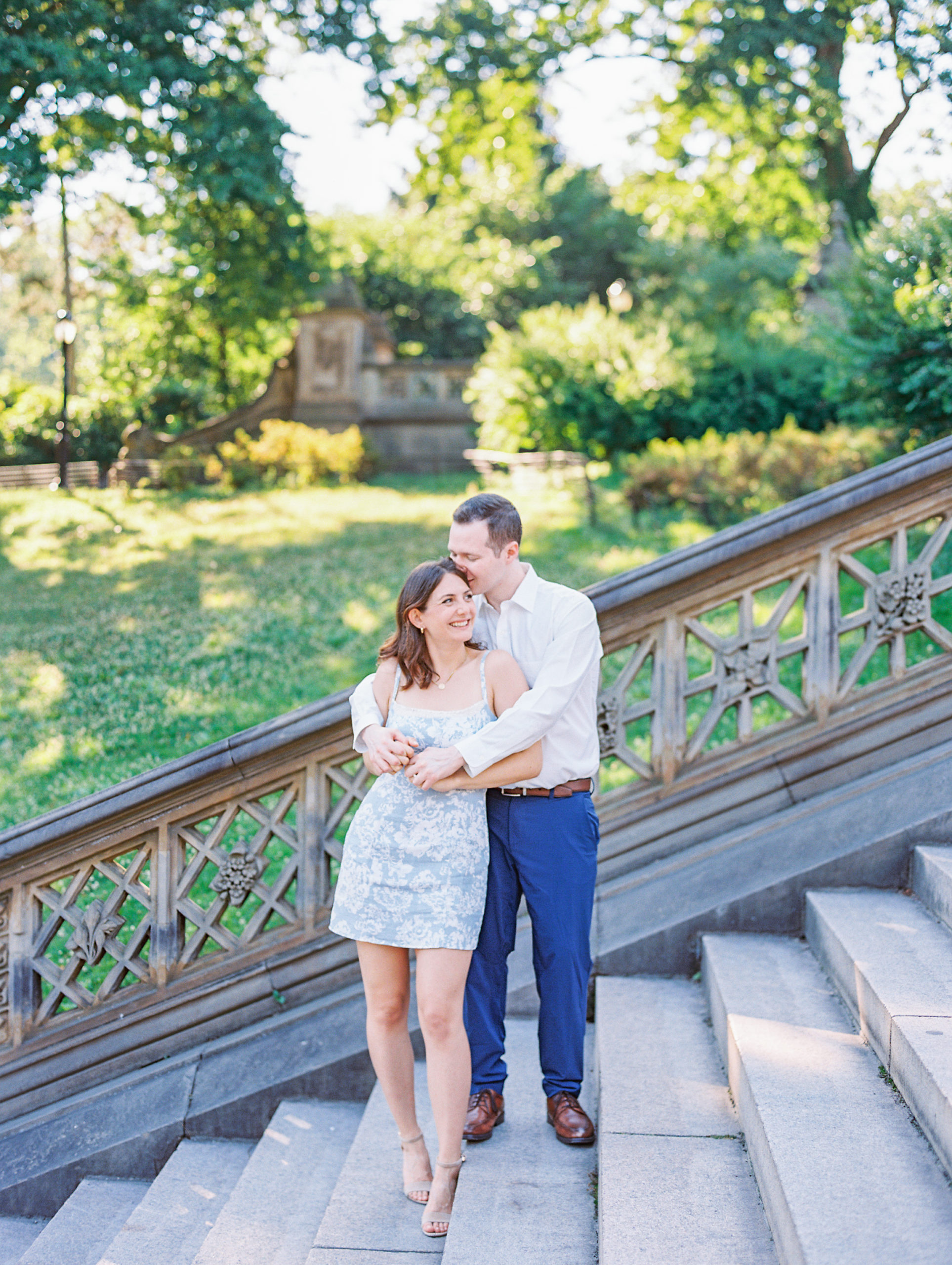 Couple holding each other and smiling on the steps of Central Park 