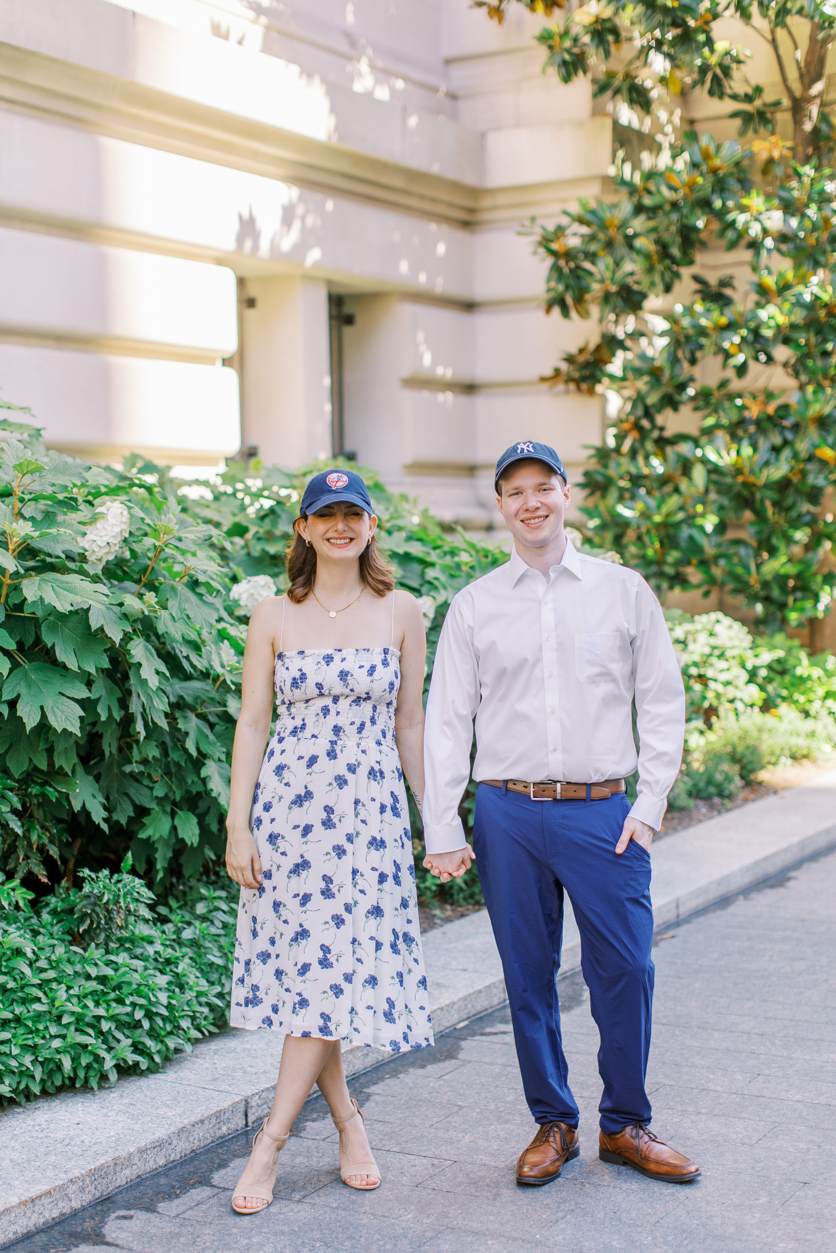 Couple holds hands wearing blue New York Yankees baseball caps for Central Park Engagement Photos