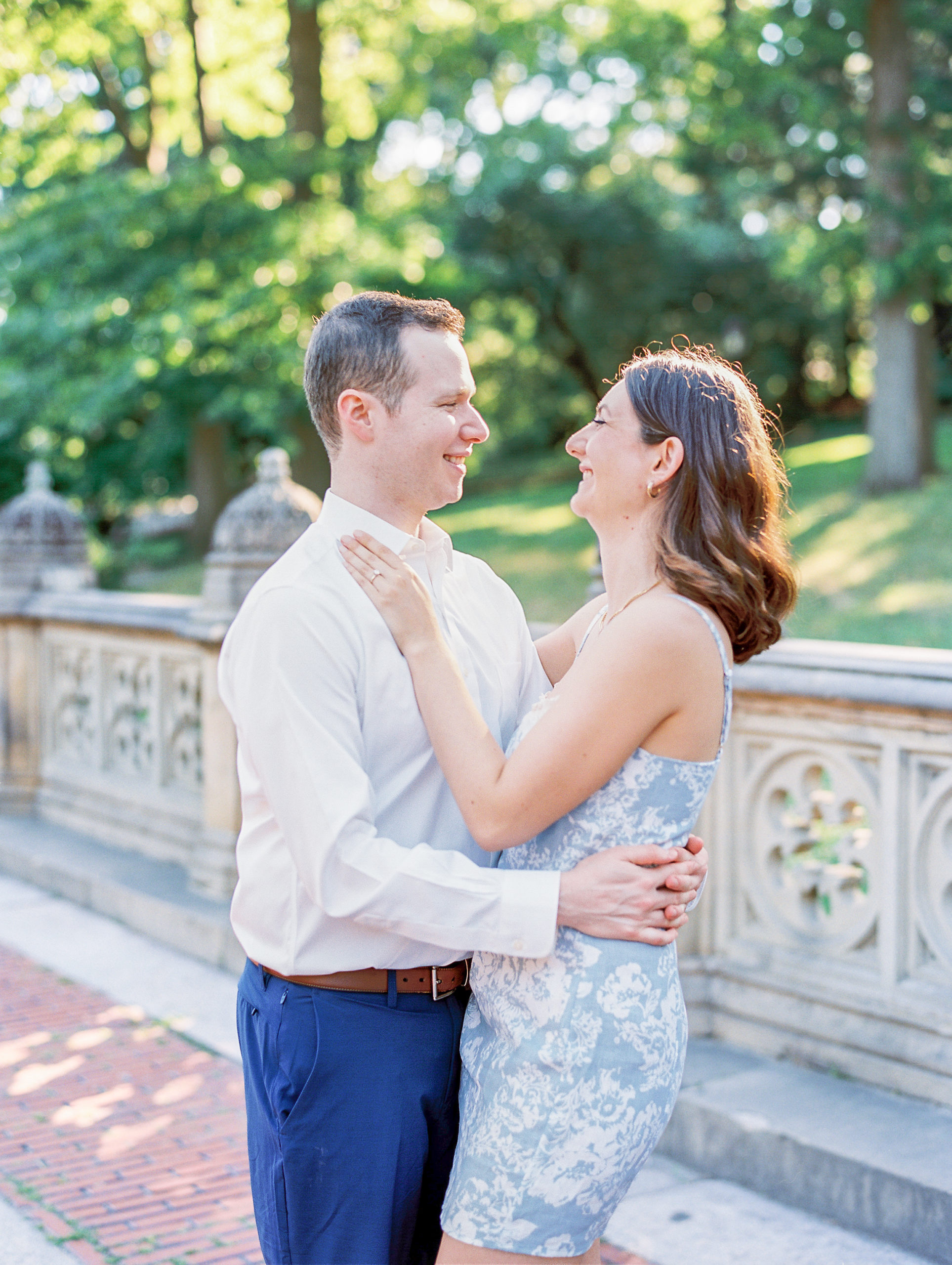 Couple embrace and smile at each other in park for Central Park Engagement Photos