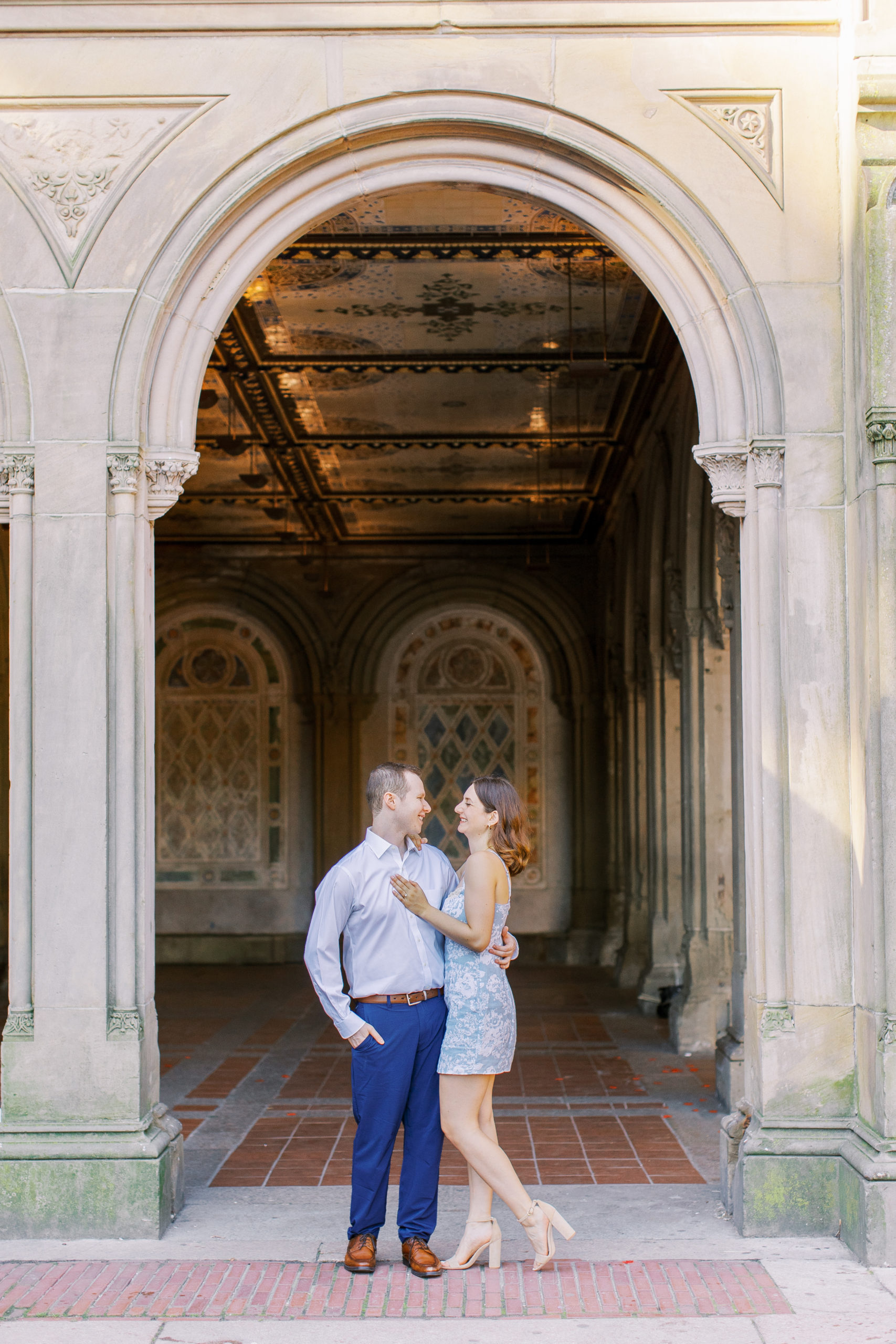 Couple embrace and smile in front of terrace archway with colorful tiles 