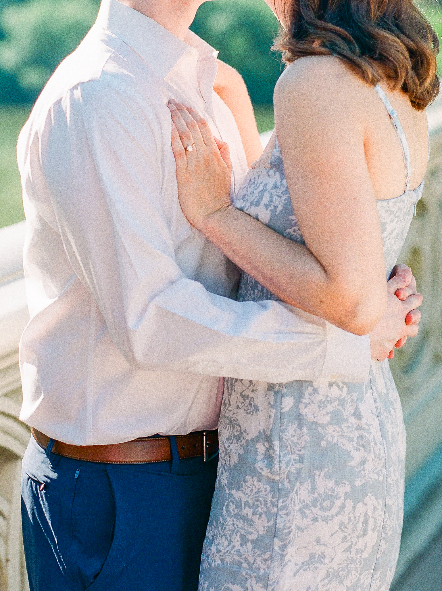 Couple embrace each other with blue and white floral dress, and navy pants and white button down 
