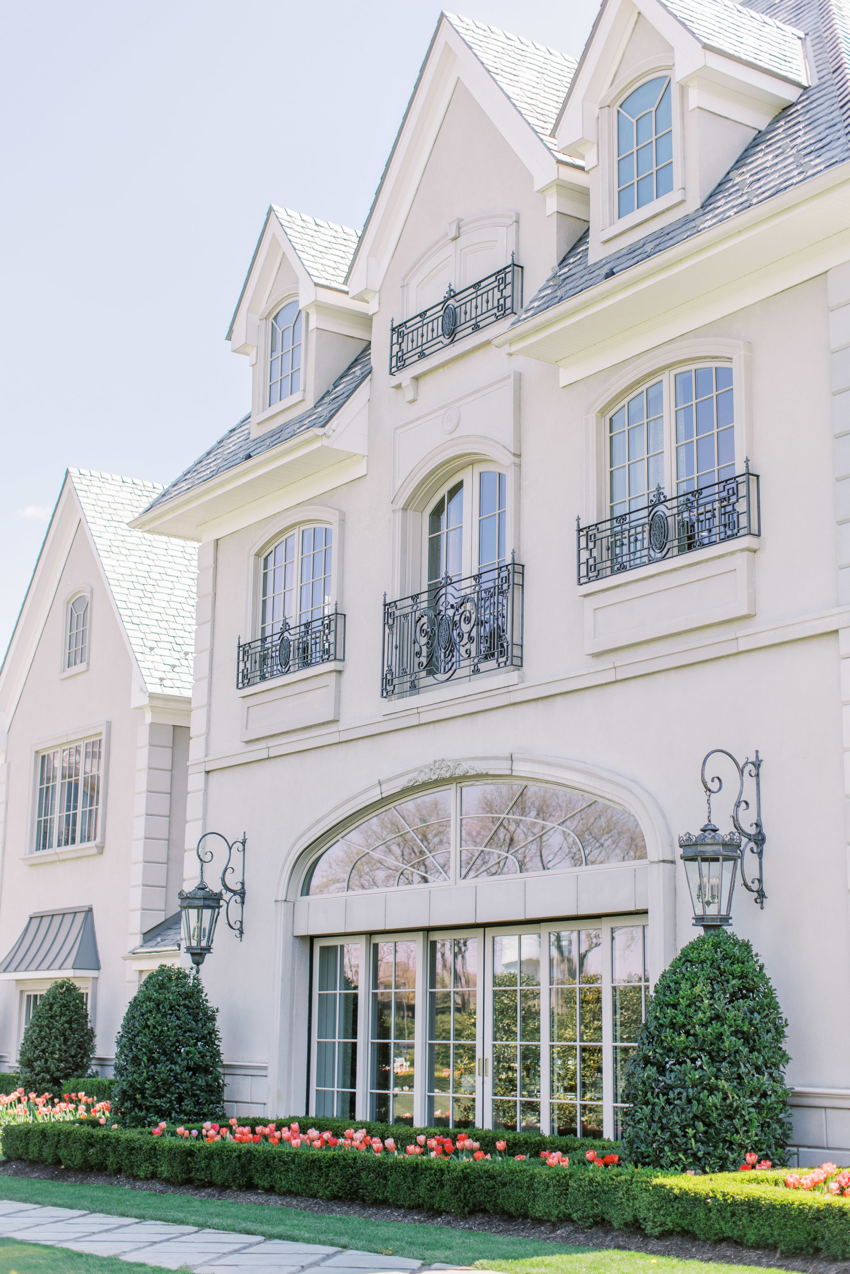 French Chateau building with large paneled windows and pink flowers 